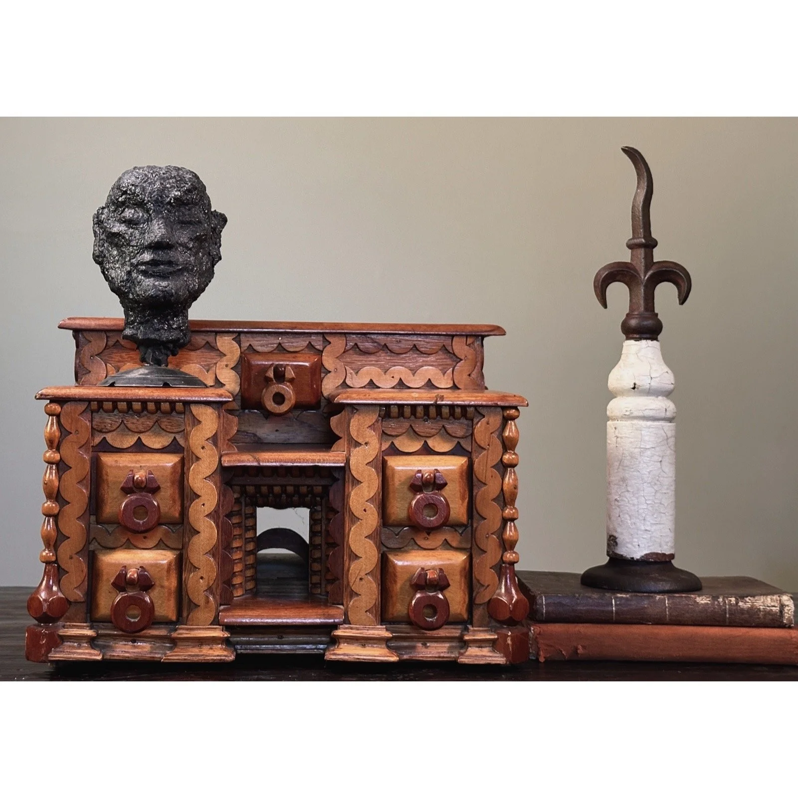 Full frontal view of a vintage folk art box with seven drawers and heavy layered scrollwork