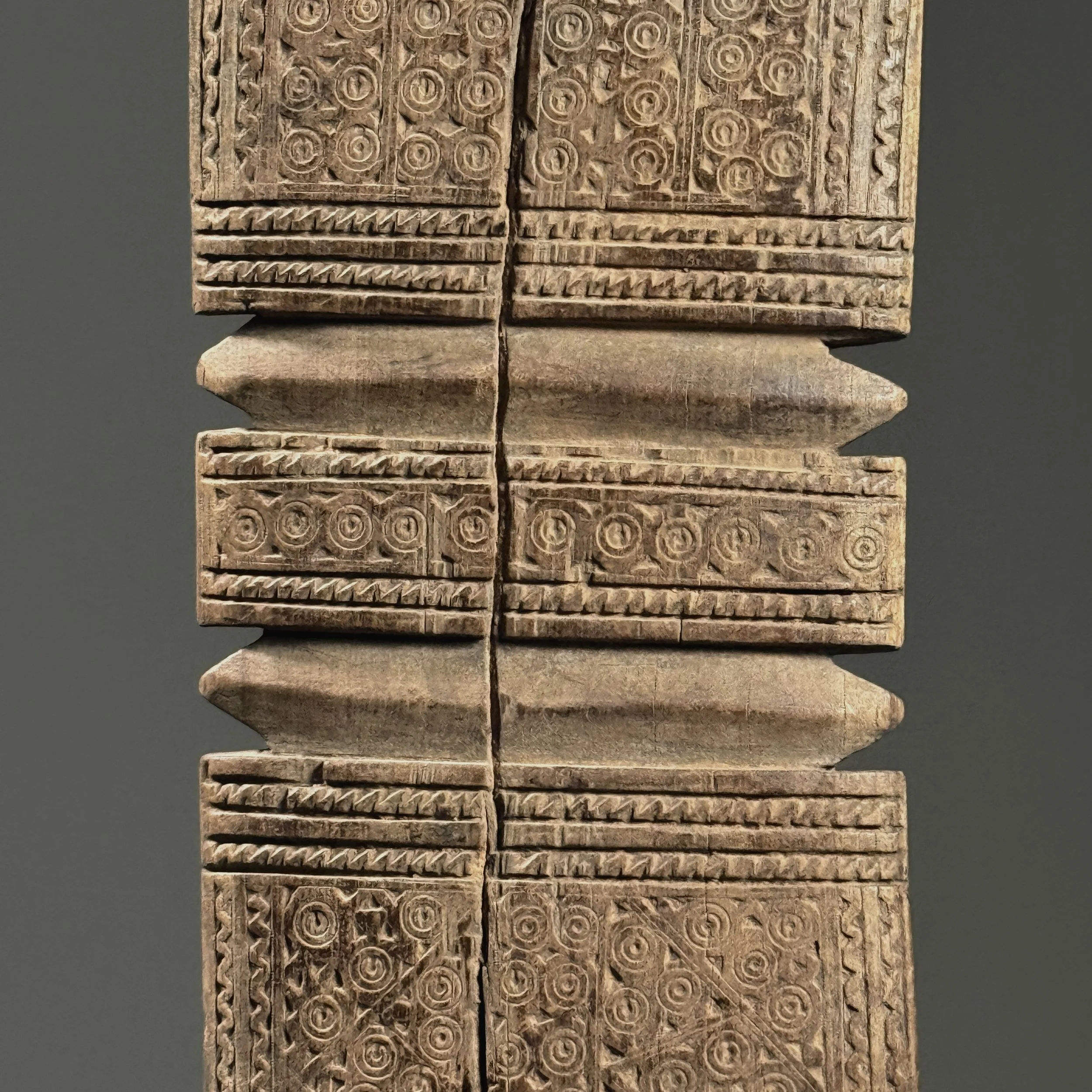 Detail of intricate incised swirling motifs on the wooden surface.