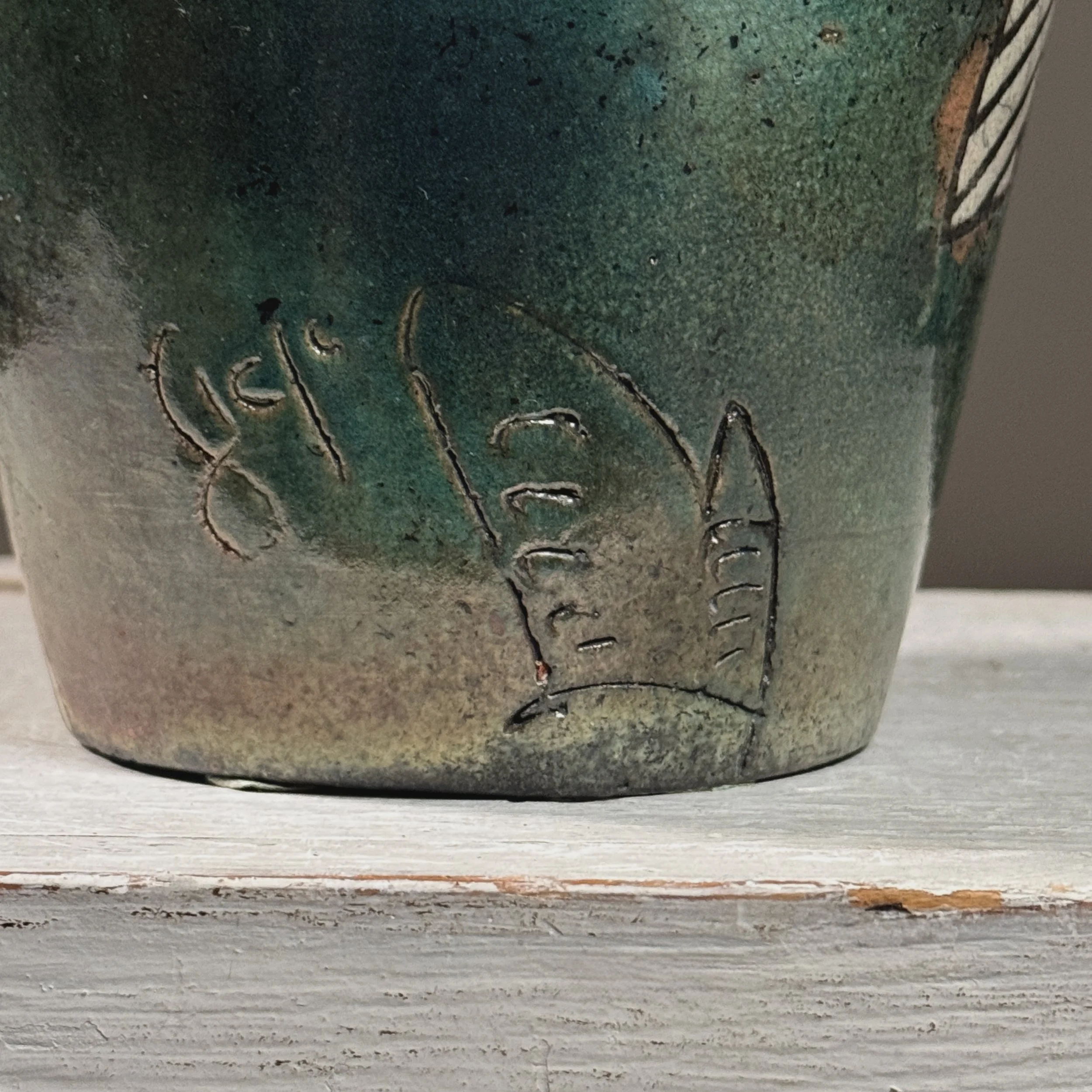 Close-up of blue-green glaze areas on vintage raku vessel with crackle surface and black line detail
