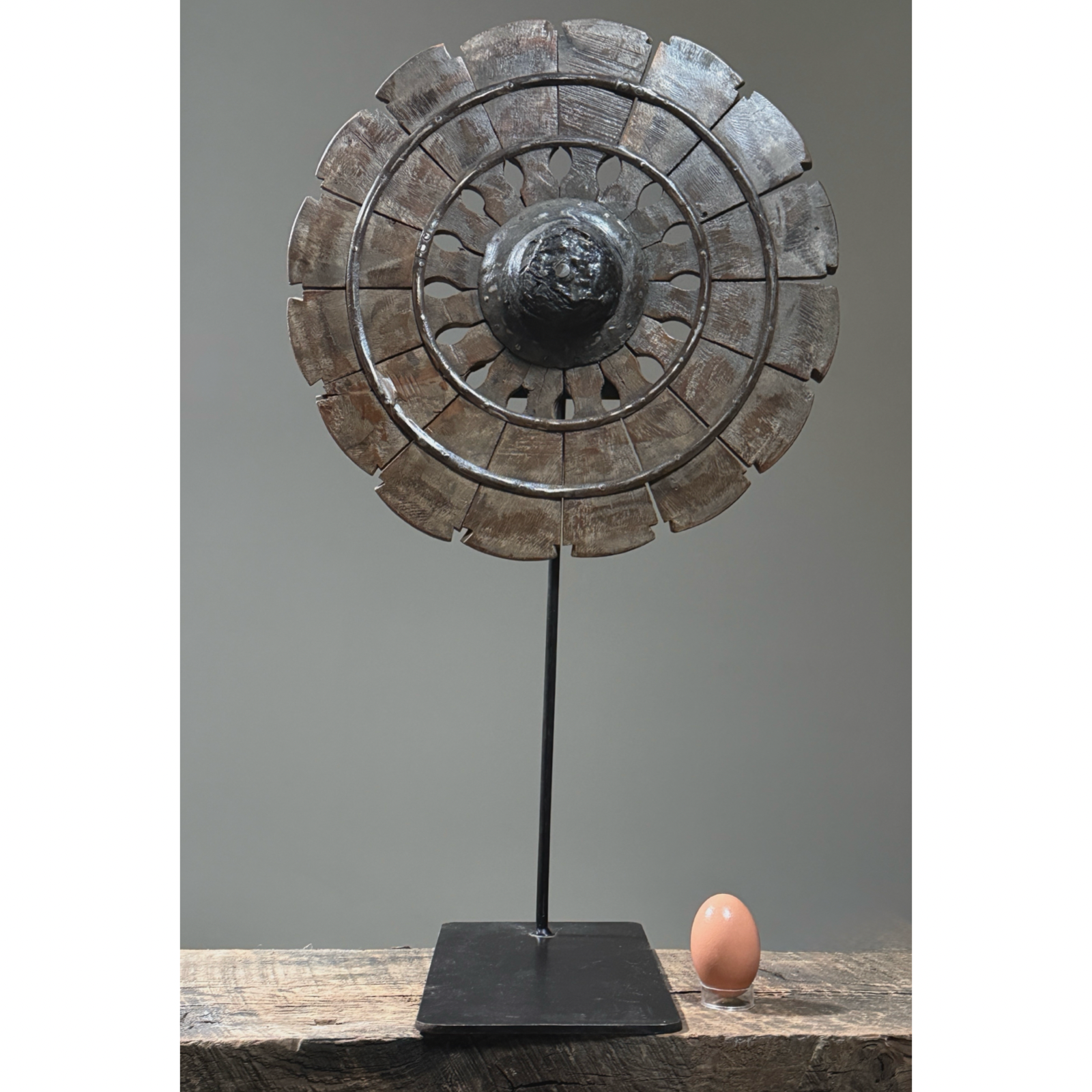 Antique hand carved folk art charkha wheel. Traditional Indian spinning wheel with egg for size reference.