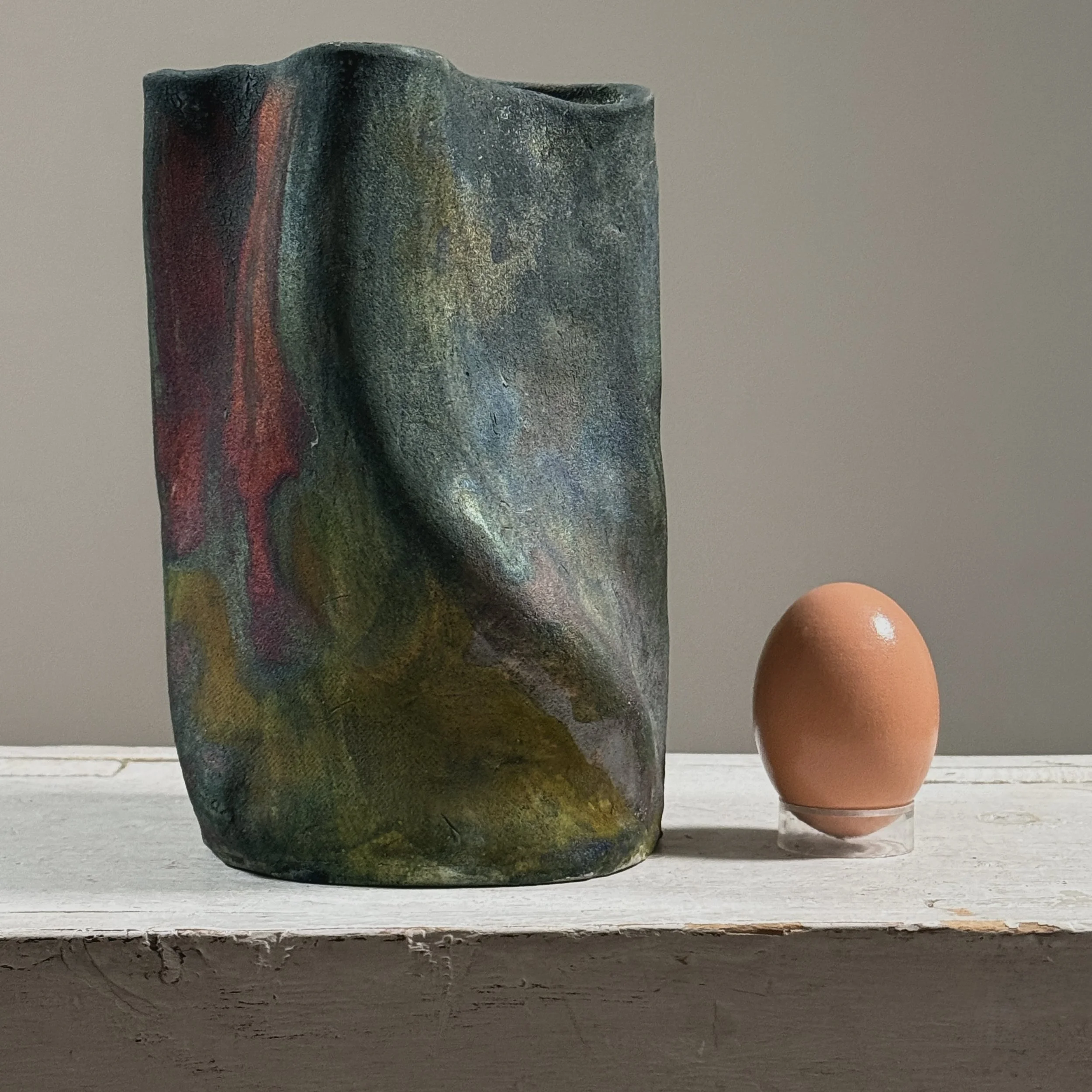 Vintage raku fired abstract fluid shaped blackware ceramic vessel, signed with egg for size reference.