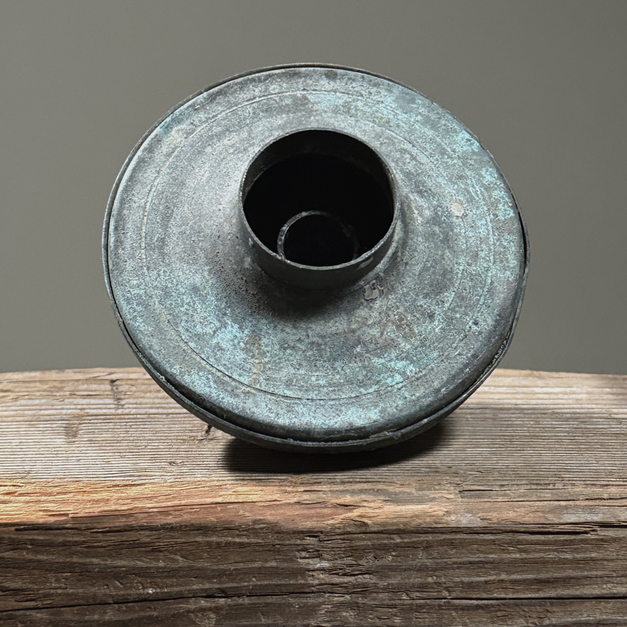 Close-up of textured surface on one Brutalist candle holder showing layered blue-green patina.