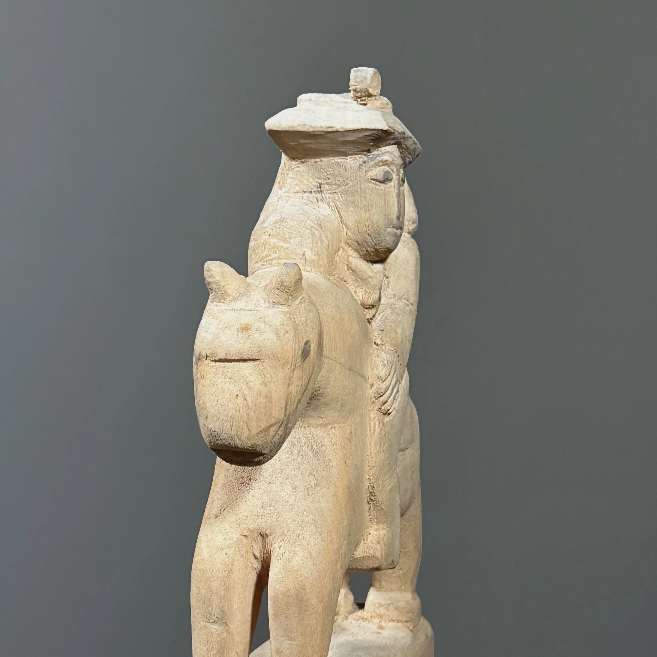 Close-up of the rider figure and the raw wood texture.