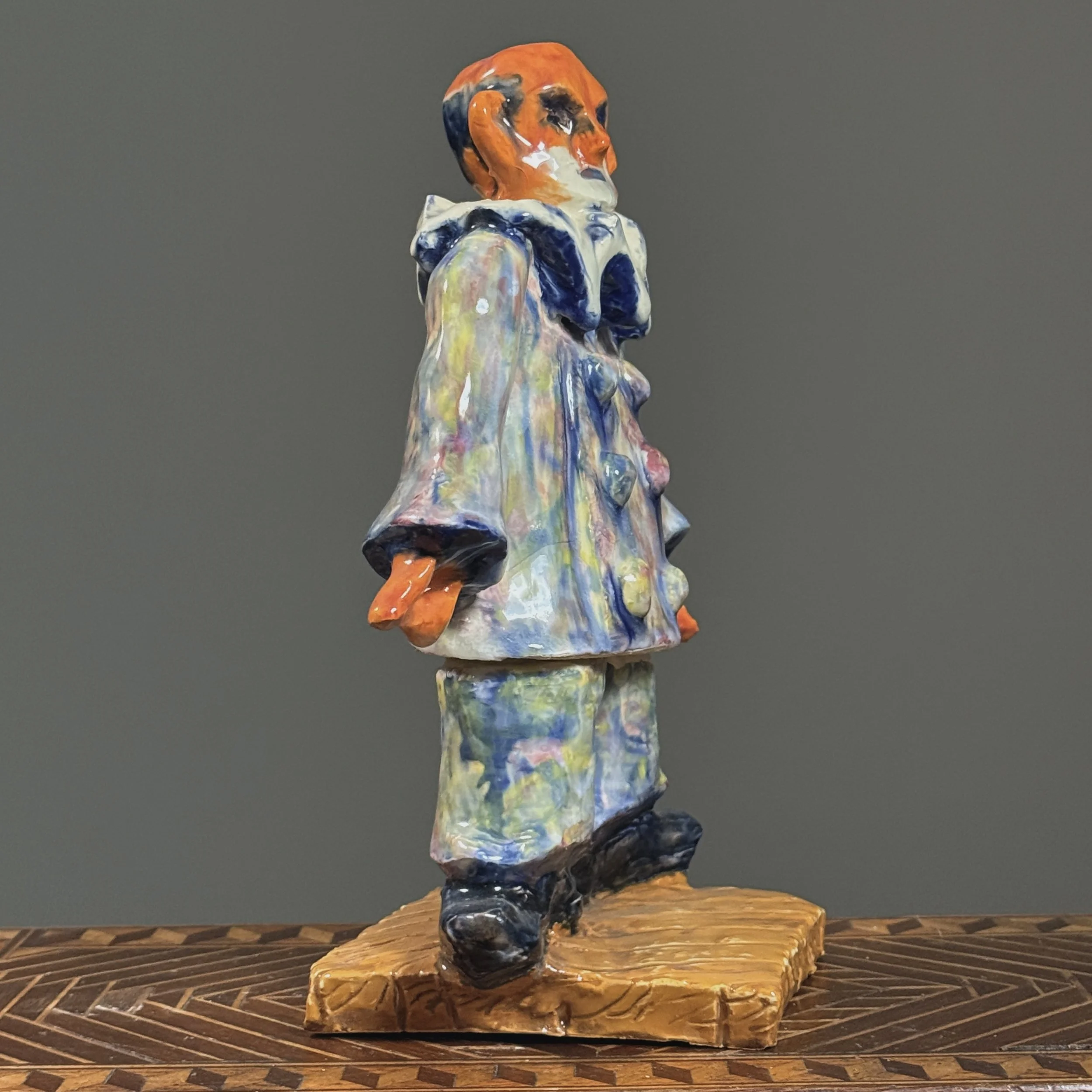 Profile view of the expressionist ceramic clown, showing the sculptural form and posture.