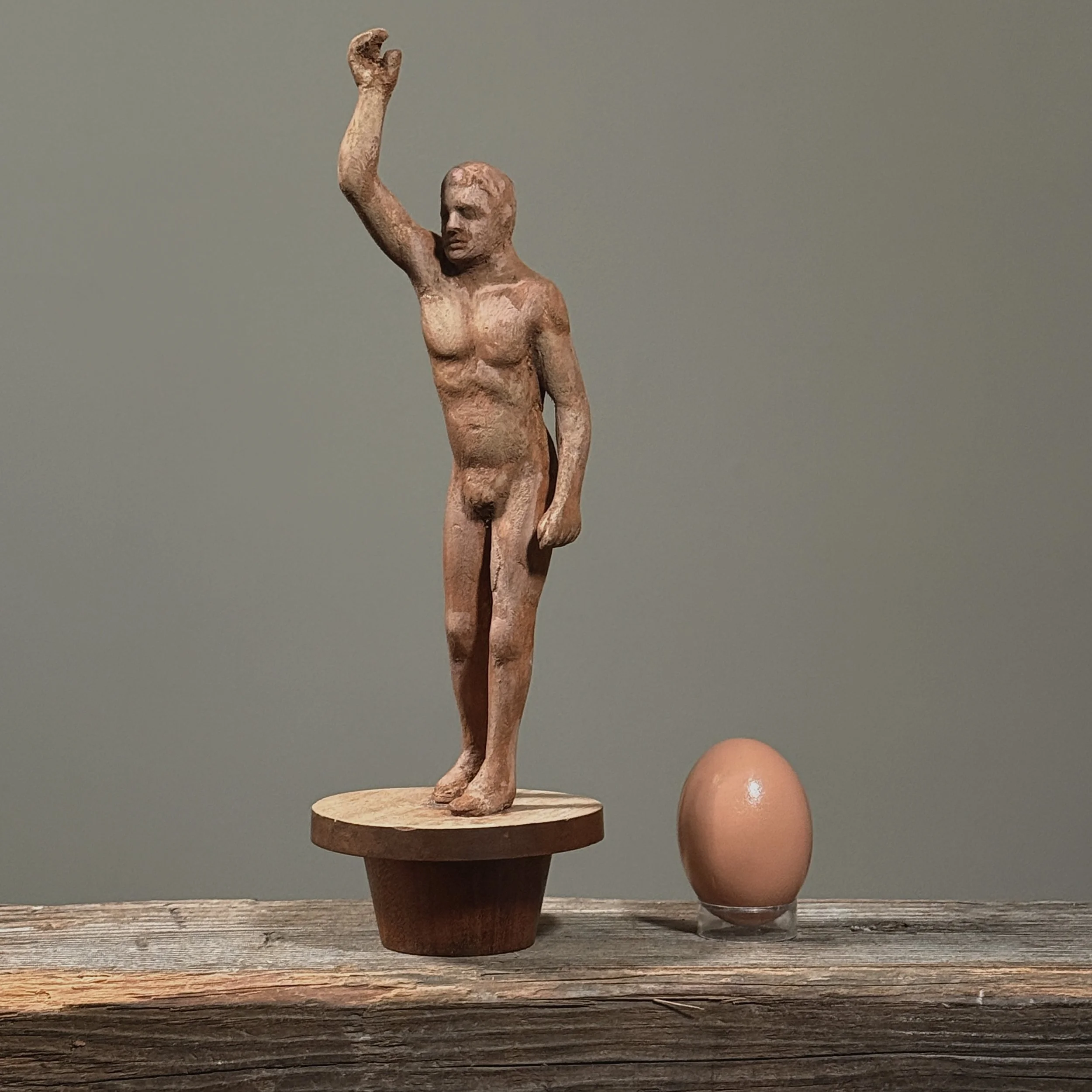 Vintage folk art sculpture with tapered wooden stand with an egg for size reference.