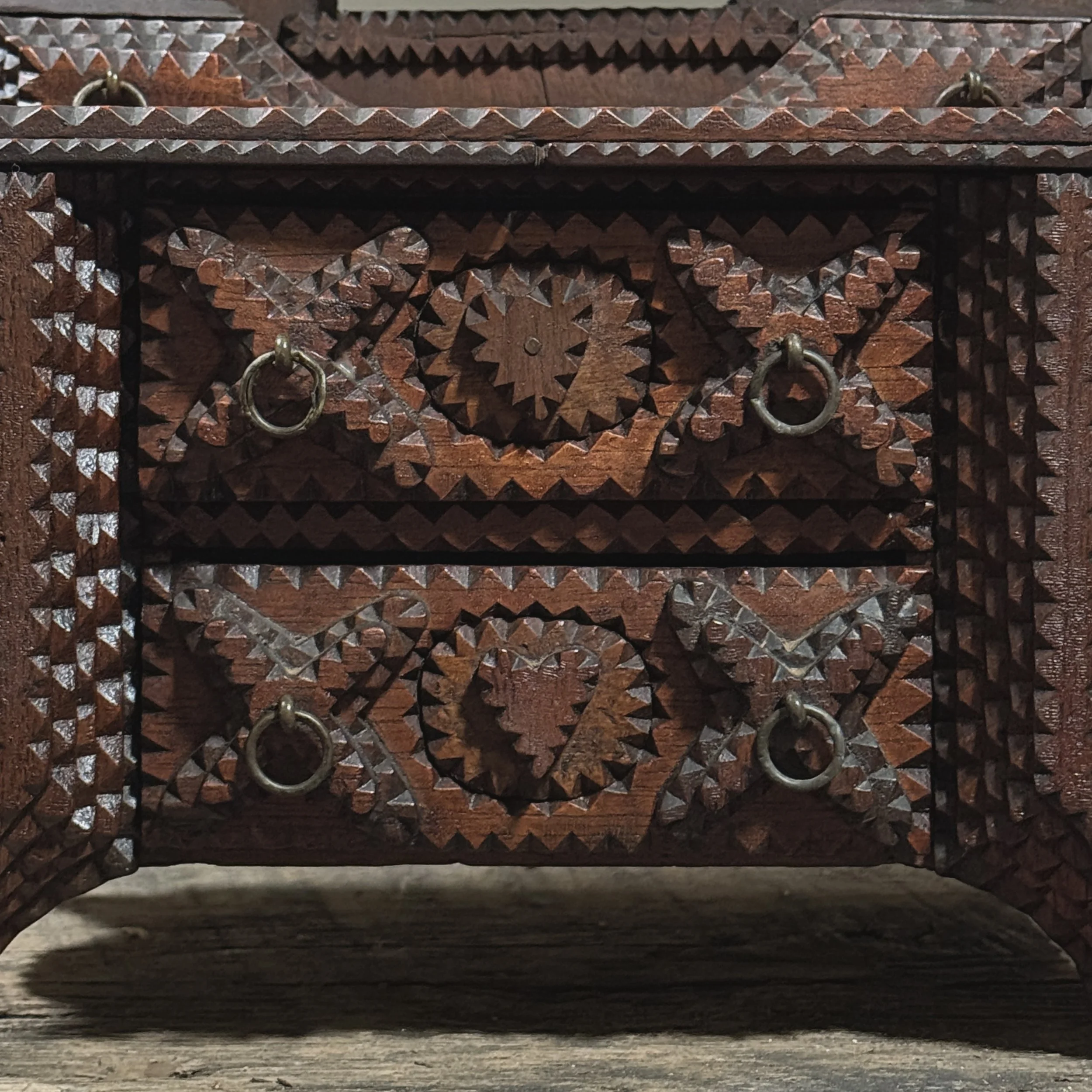 Close-up of dimensional stepped “X” carvings around drawer pulls