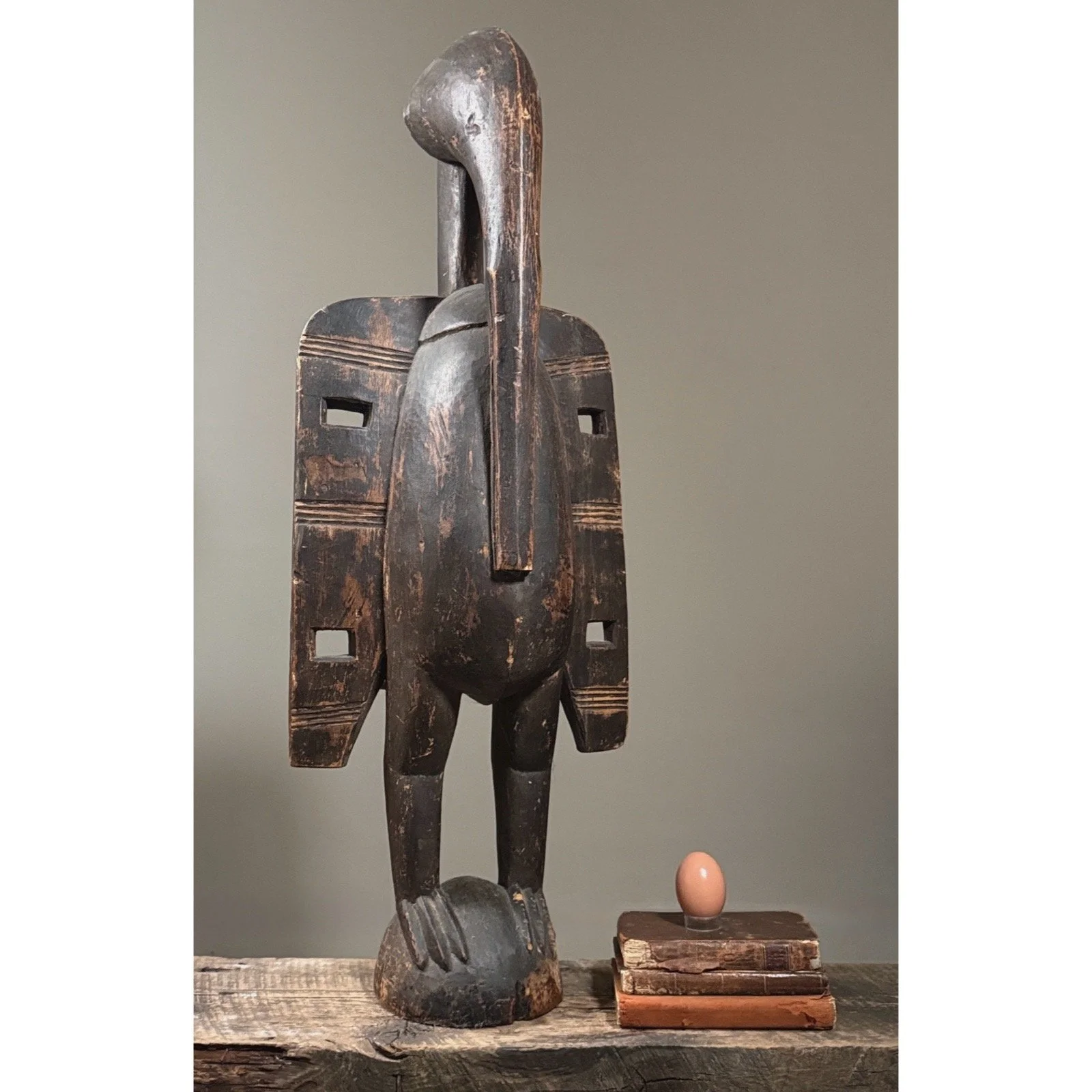 Full height view of tall Senufo Calao bird carving with egg for size reference.