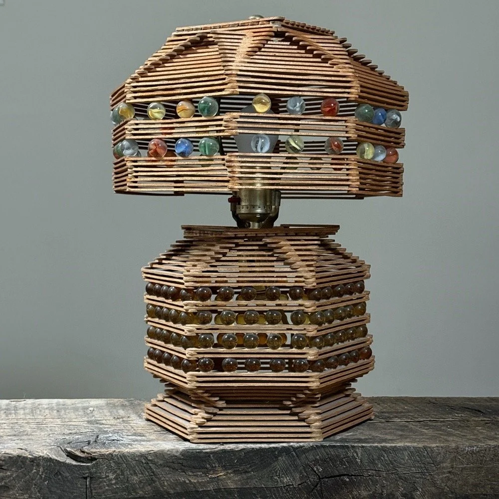 Full front view of the functional vintage popsicle stick and marble folk art table lamp.