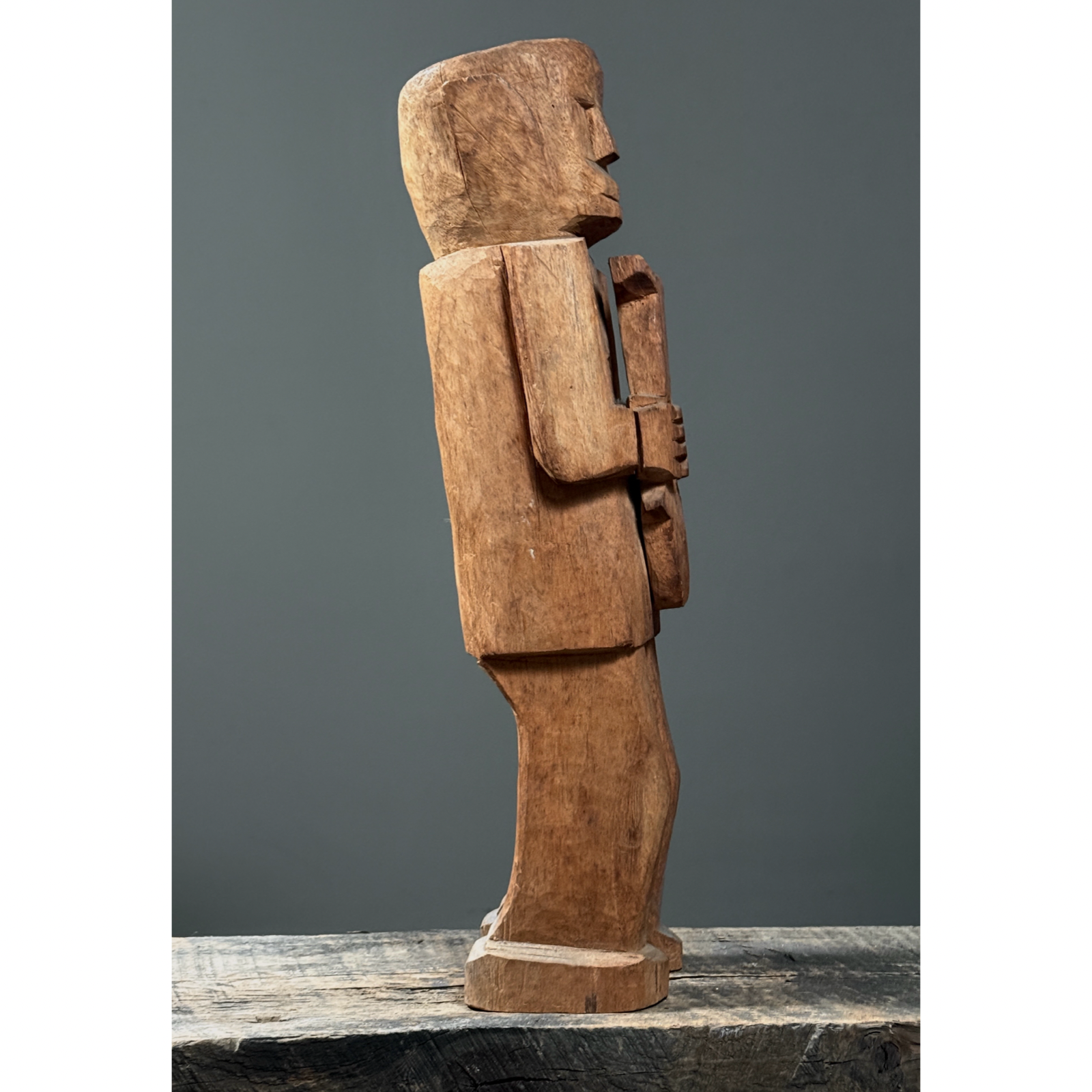 Front view of hand-carved wood folk art figure of man holding a fish