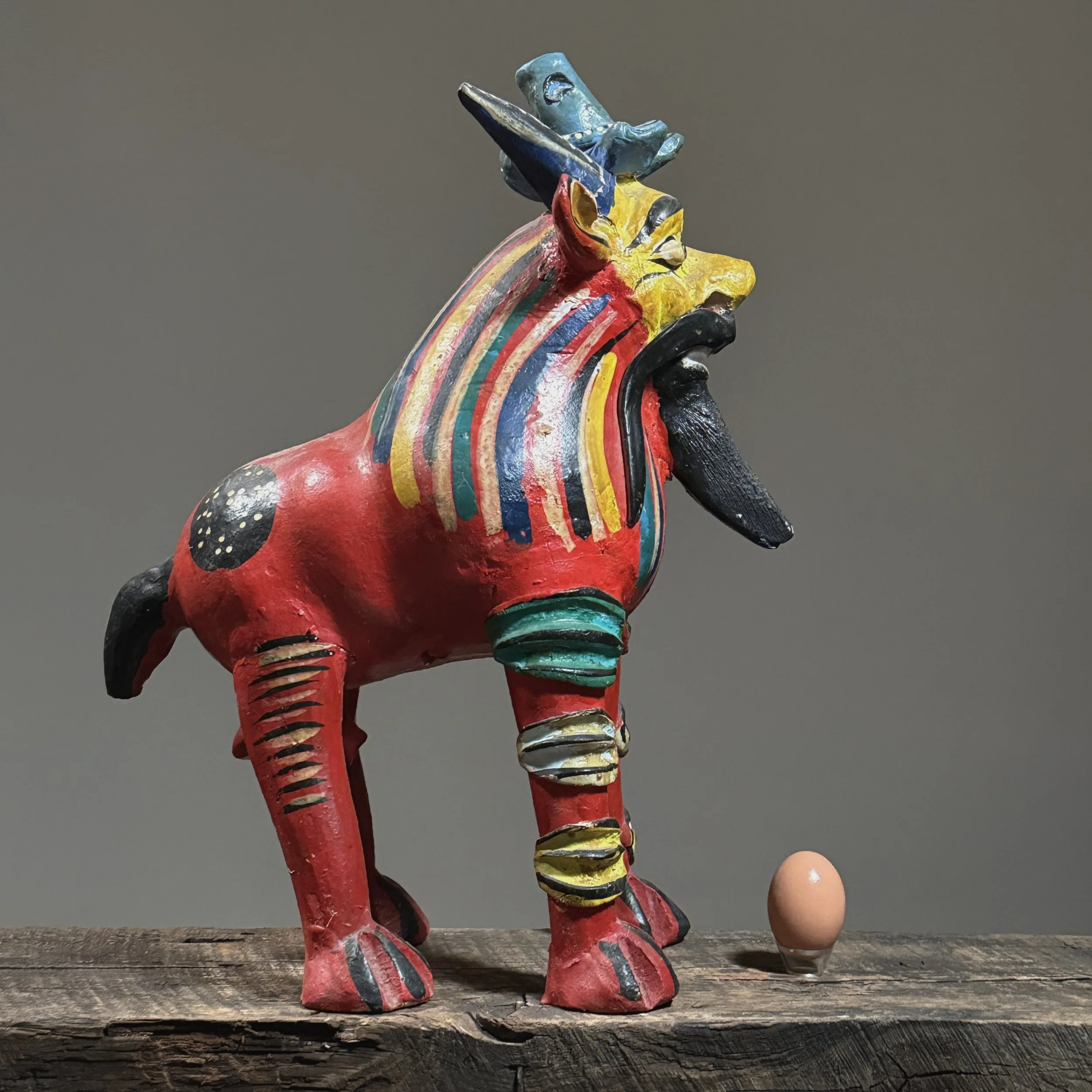 Side profile of a vintage Mexican folk art monster sculpture by renowned artist Candelario Medrano with egg for size reference.
