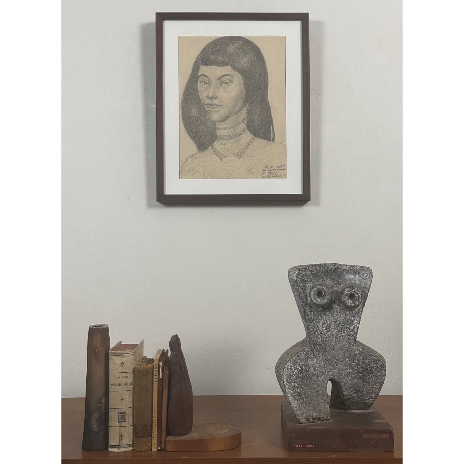Full frontal view of a framed graphite portrait of a young woman by Juan Carlos Iramain in an interior vignette.