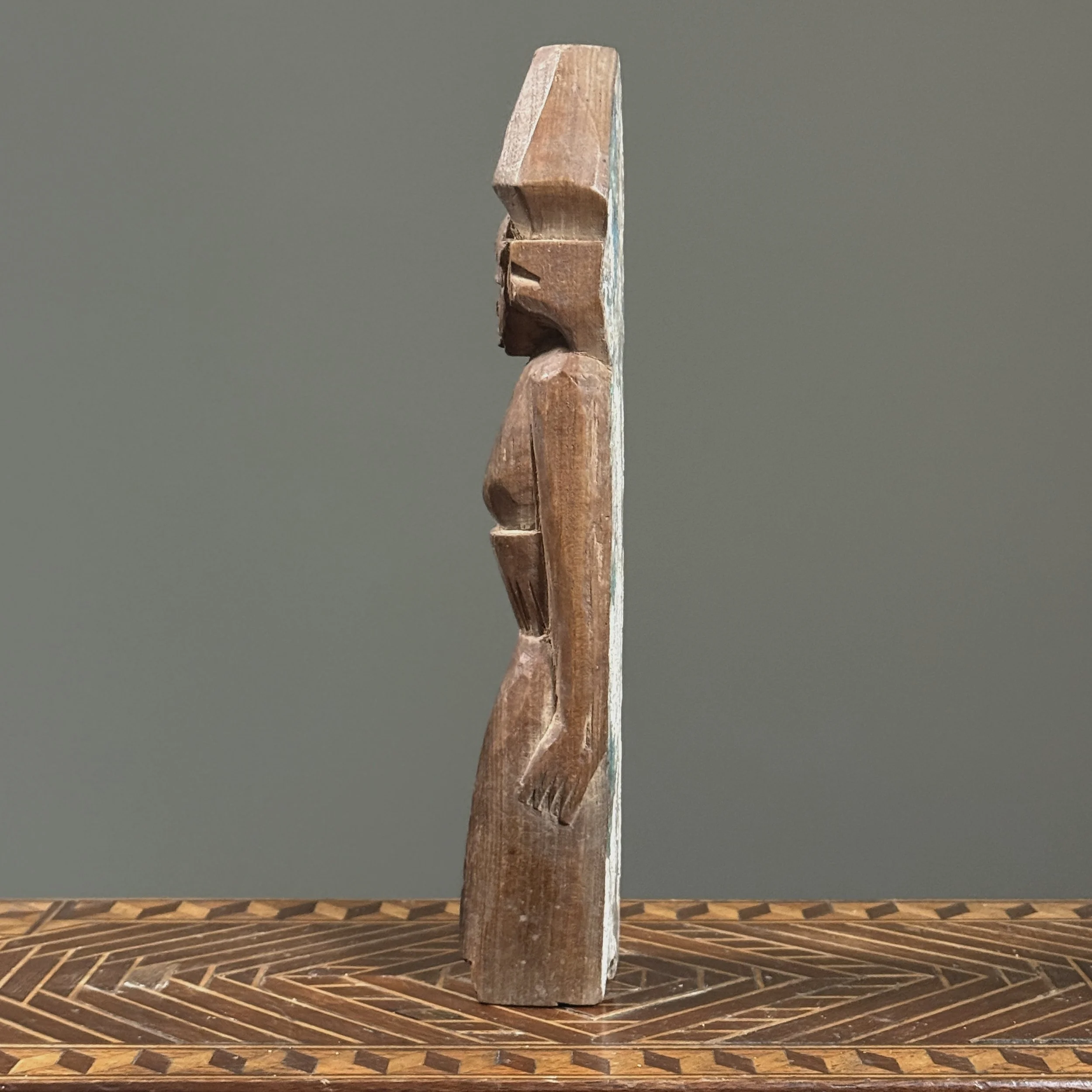 Flat-backed brown wooden female figure from Southeast Asia, side view.