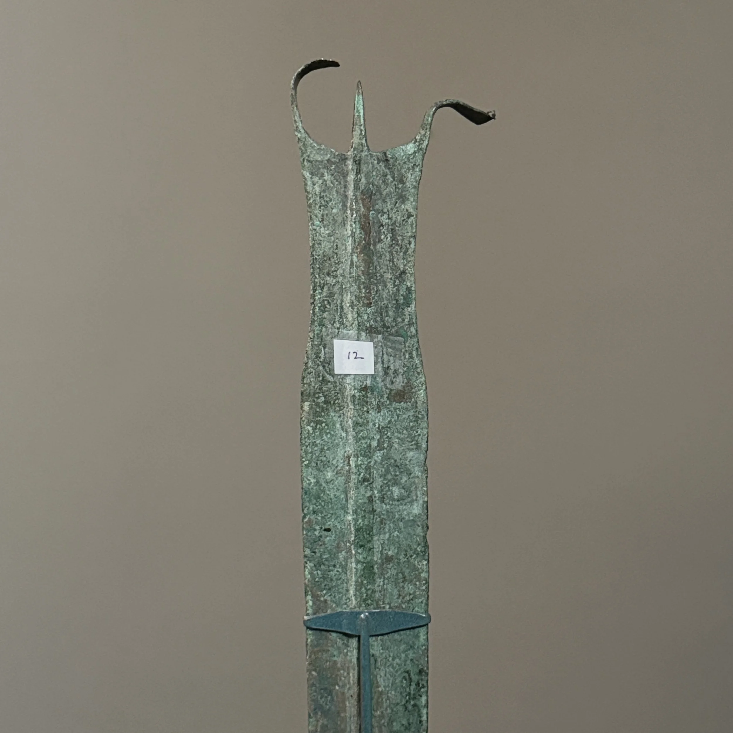 Close-up detail of the dagger's distinctive tri-pointed finial with curved horns.