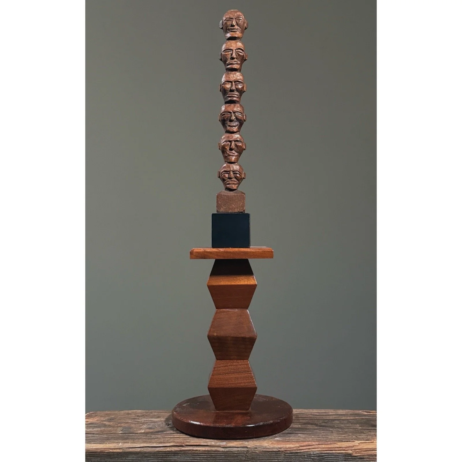 Antique hand-carved wooden head totem on a modernist wood stand.