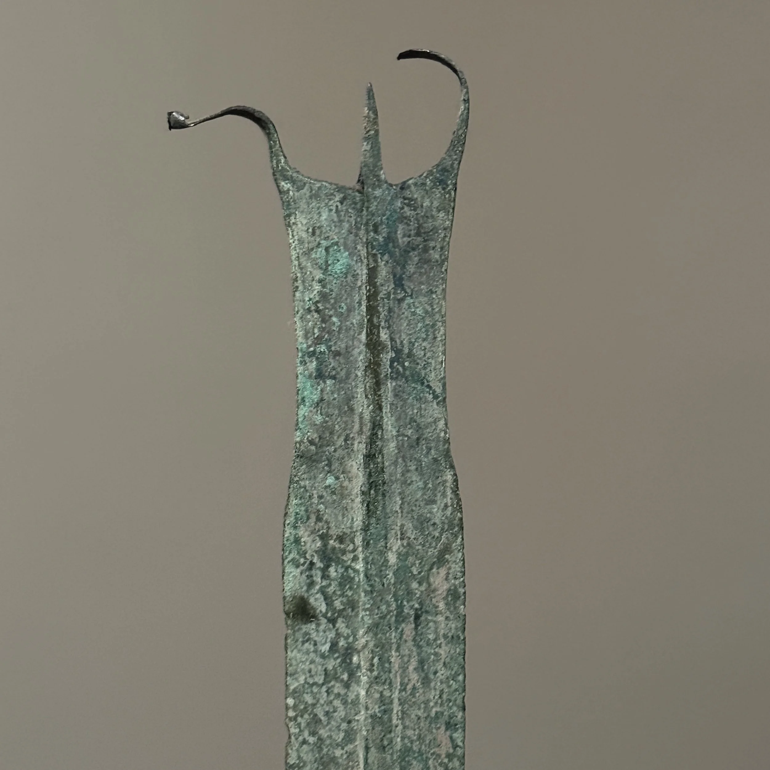 Close-up detail of the dagger's distinctive tri-pointed finial with curved horns.