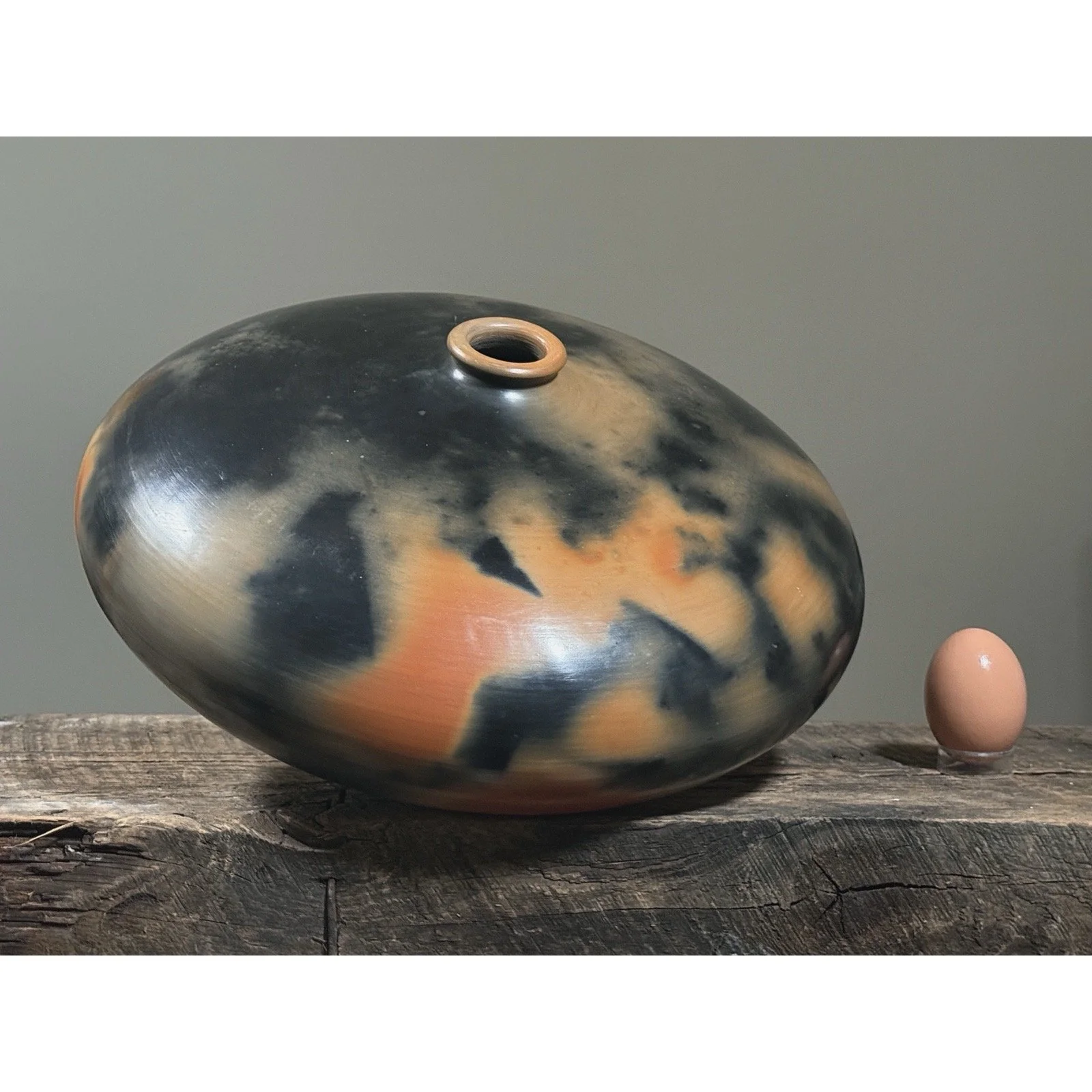 Large hand-turned seed pot with burnished surface and stout neck with egg for size reference.