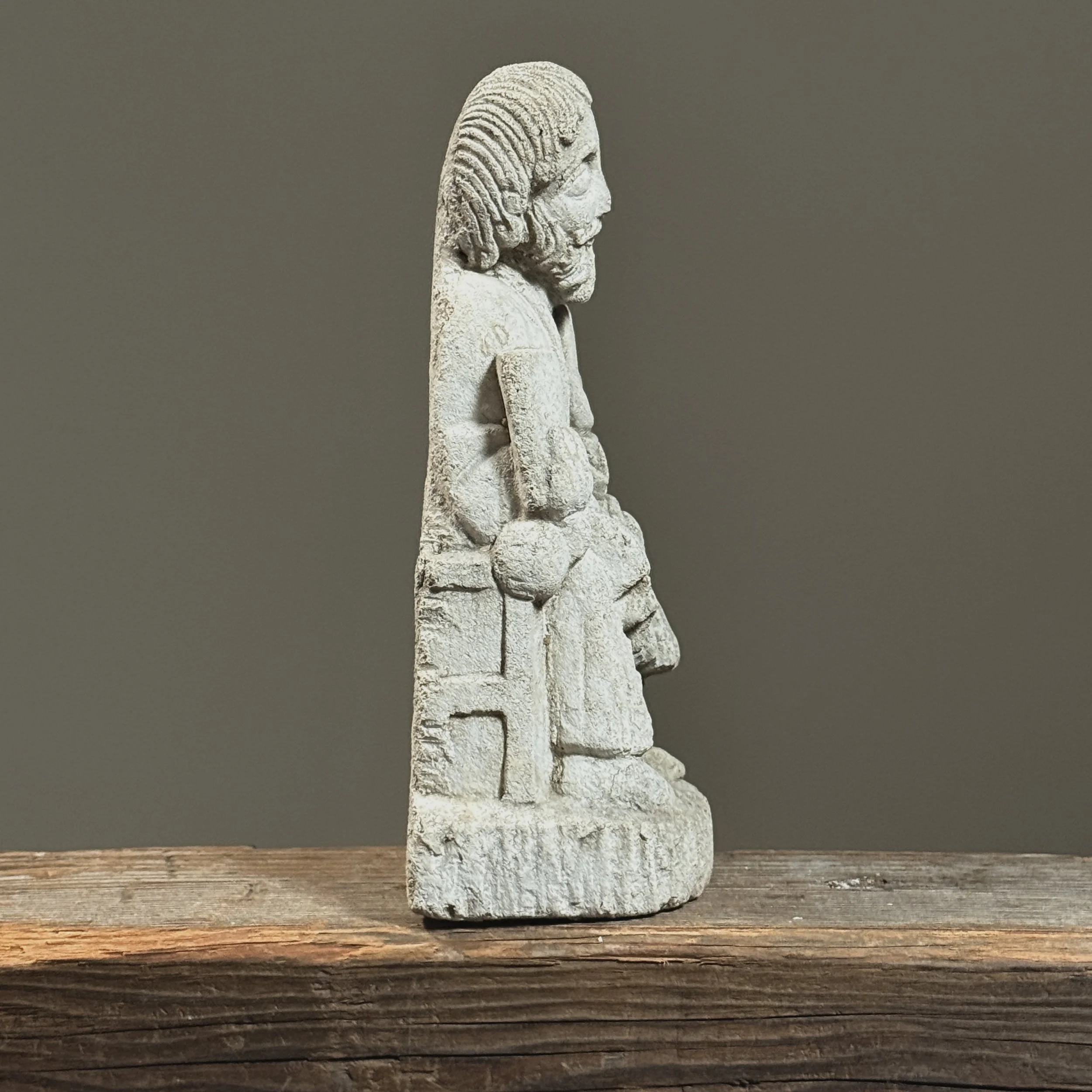 Side view of the sculpture, highlighting the rigid drapery folds and vertical composition.