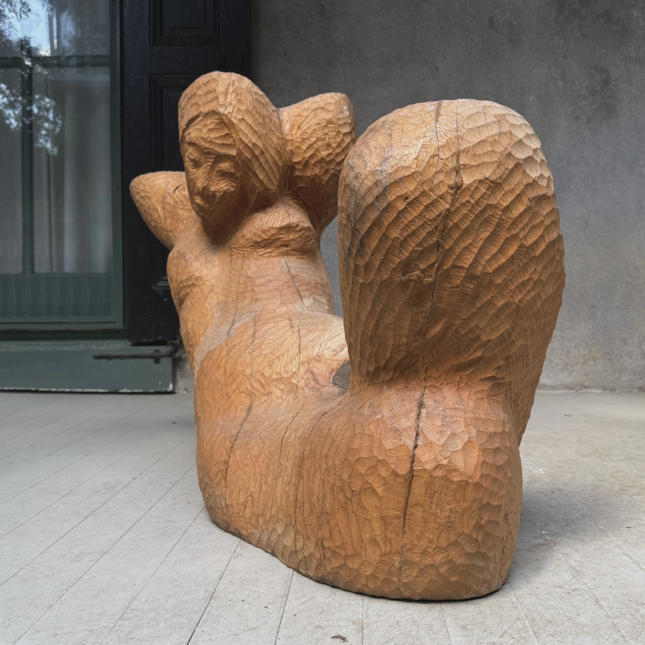 Full frontal view of a vintage monumental modernist wood sculpture of a reclining woman