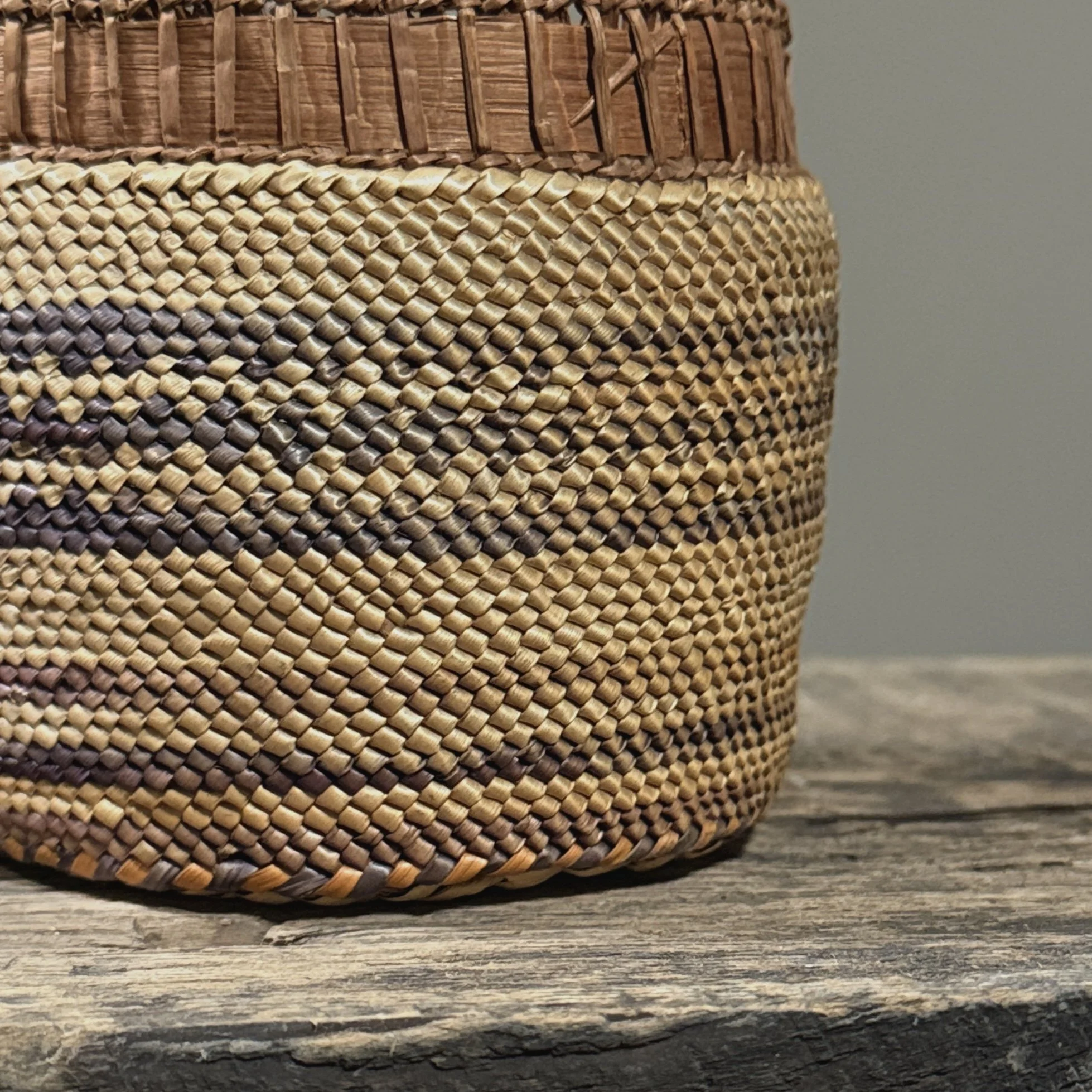 Close-up detail of wrapped twining technique and purple-dyed grass on an antique Makah basket