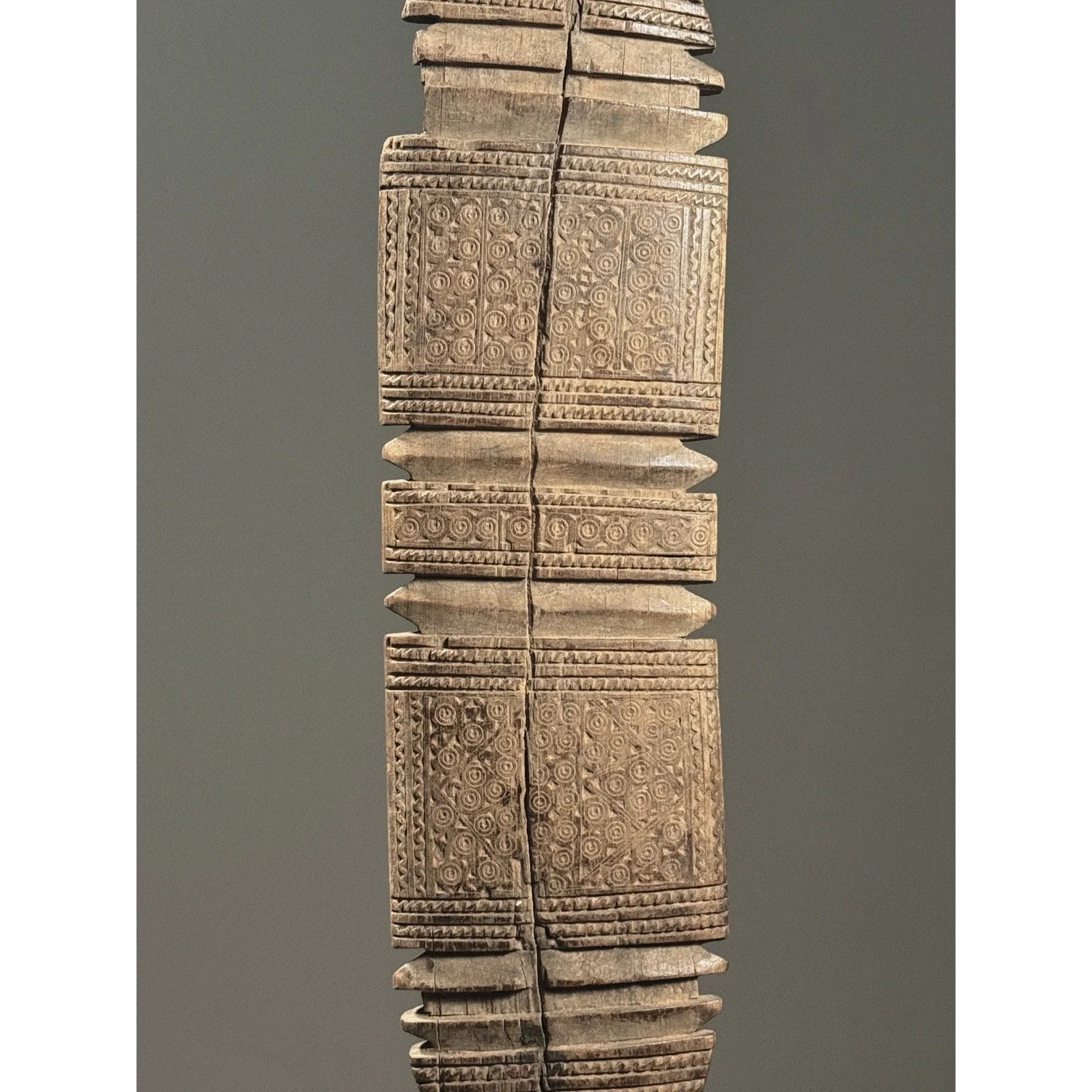 Detail of intricate incised swirling motifs on the wooden surface.