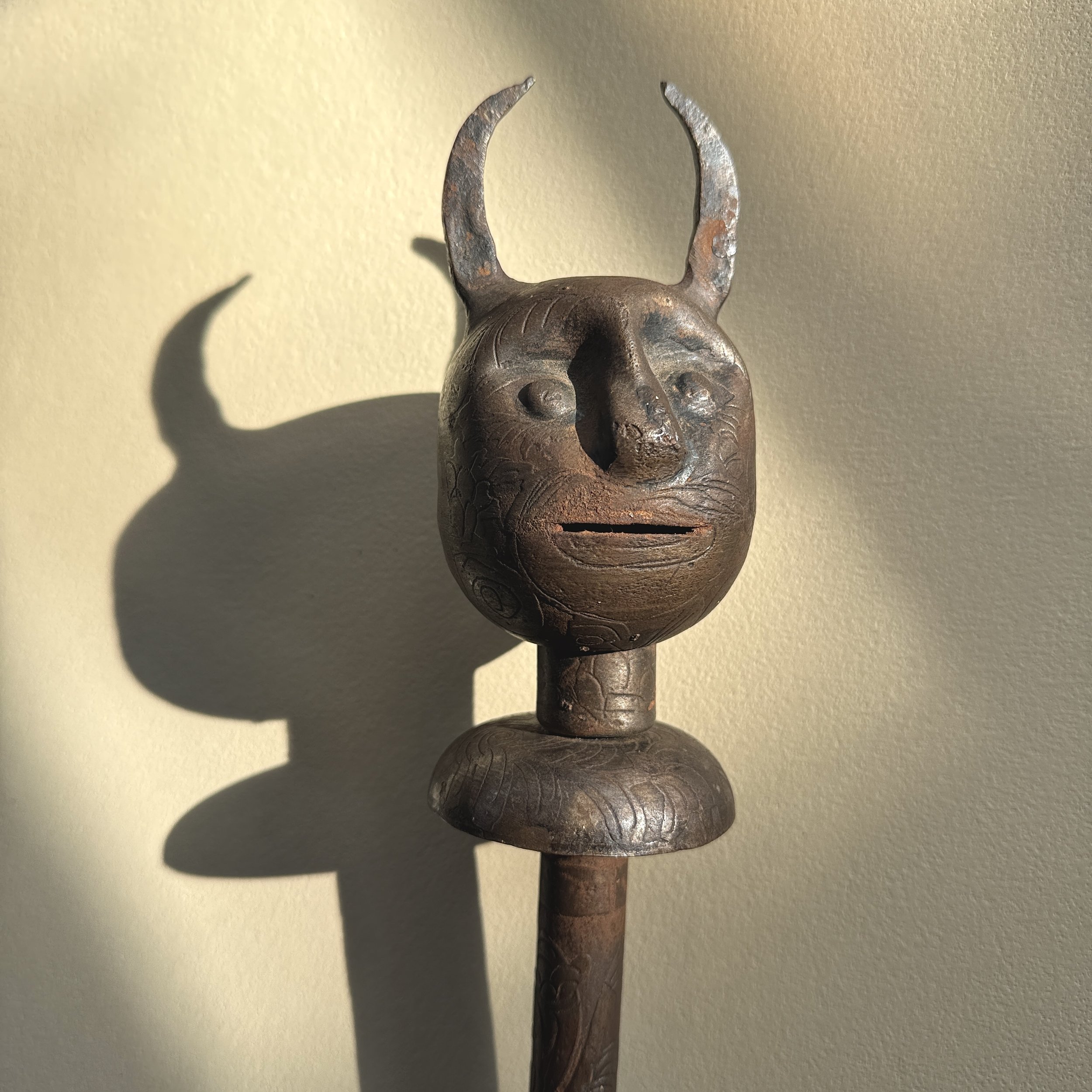 Close-up of forged devil face mace head showing etched features and dark patina.