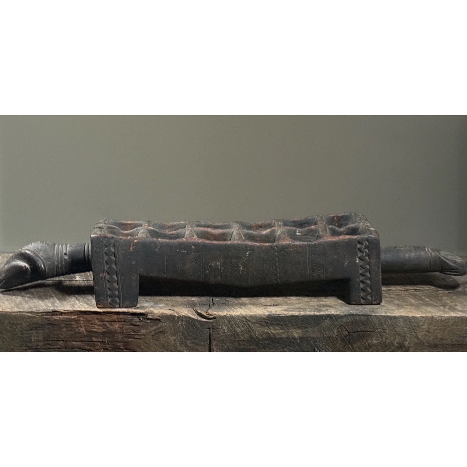 Profile view of African carved mancala board showing elongated animal form