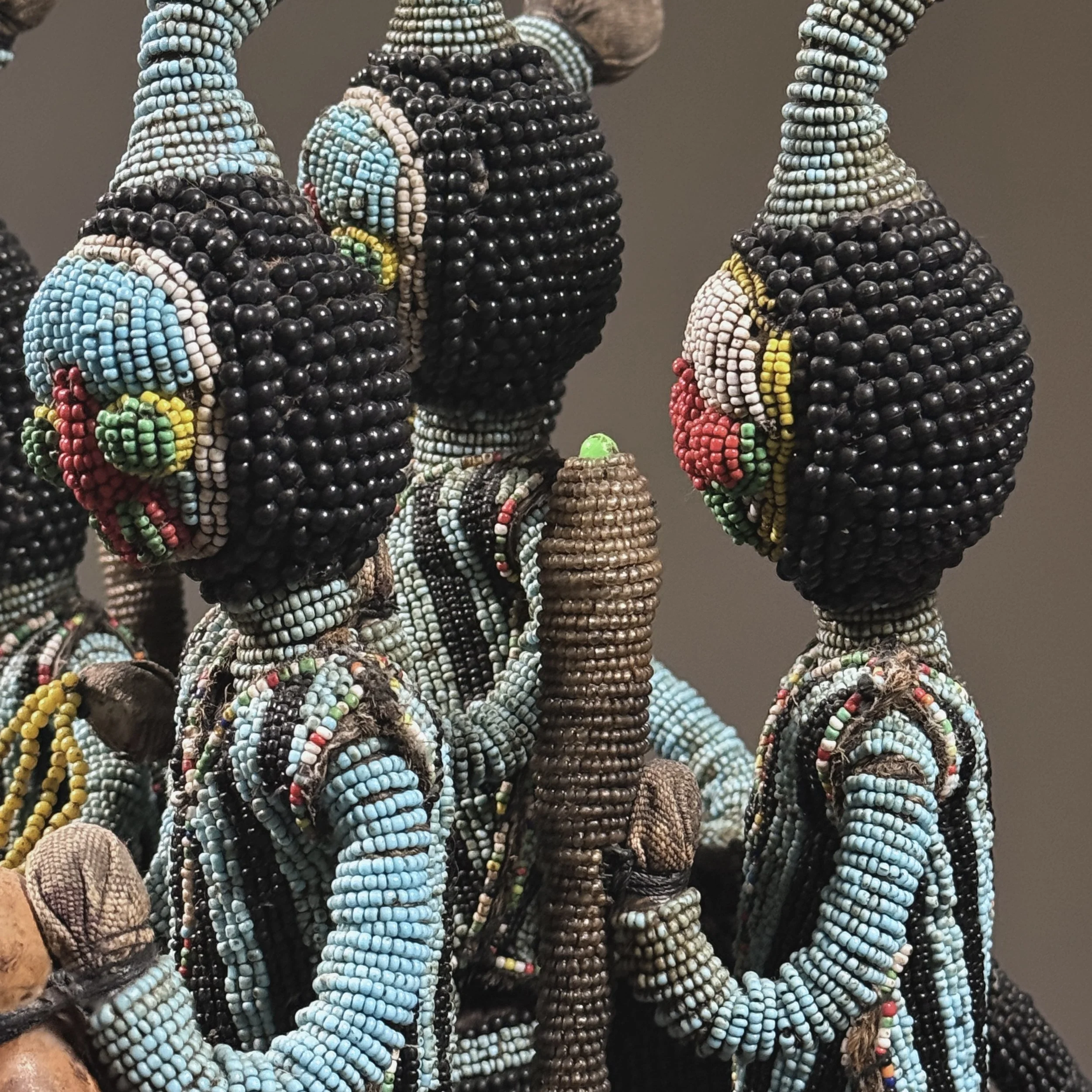 Detail of flanking attendant figures bearing gourds and wands on a vintage African headdress