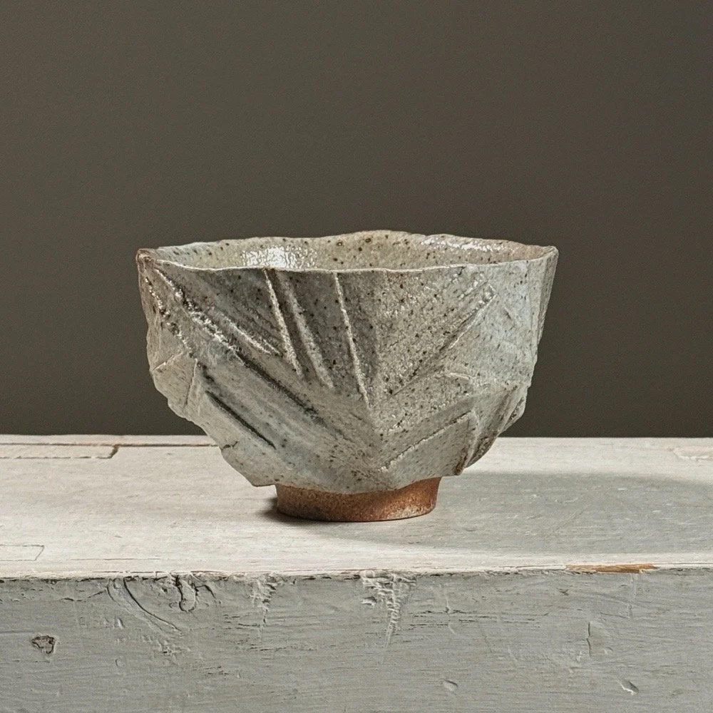 Front view of a vintage Brutalist geometric carved ceramic footed bowl.