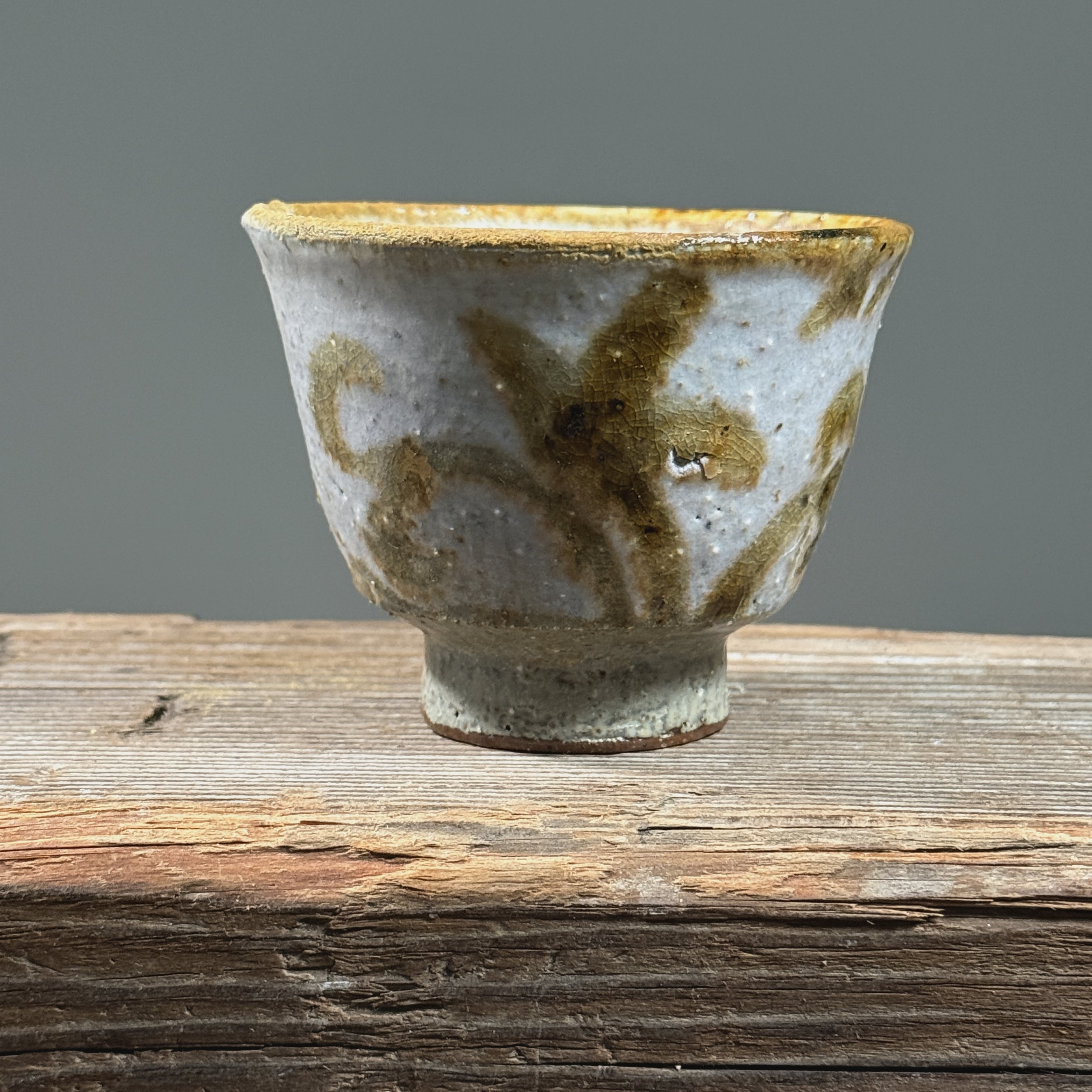 Pale purple-pink yunomi cup. Matte surface. Flourish design painted near rim on exterior wall.