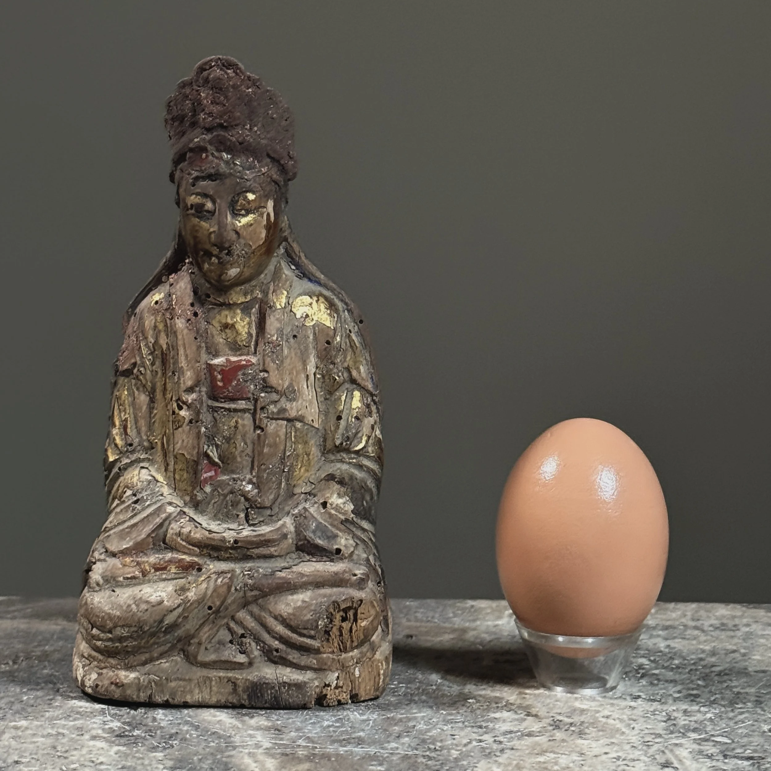 Front view of a late Ming Dynasty seated giltwood figure, likely Guanyin with egg for size reference.