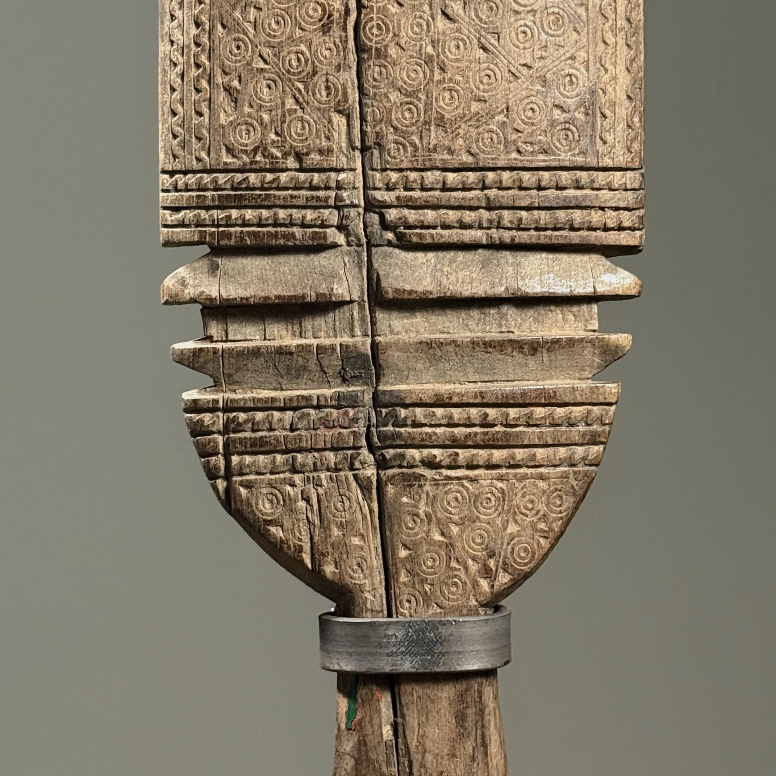 Detail of intricate incised swirling motifs on the wooden surface.