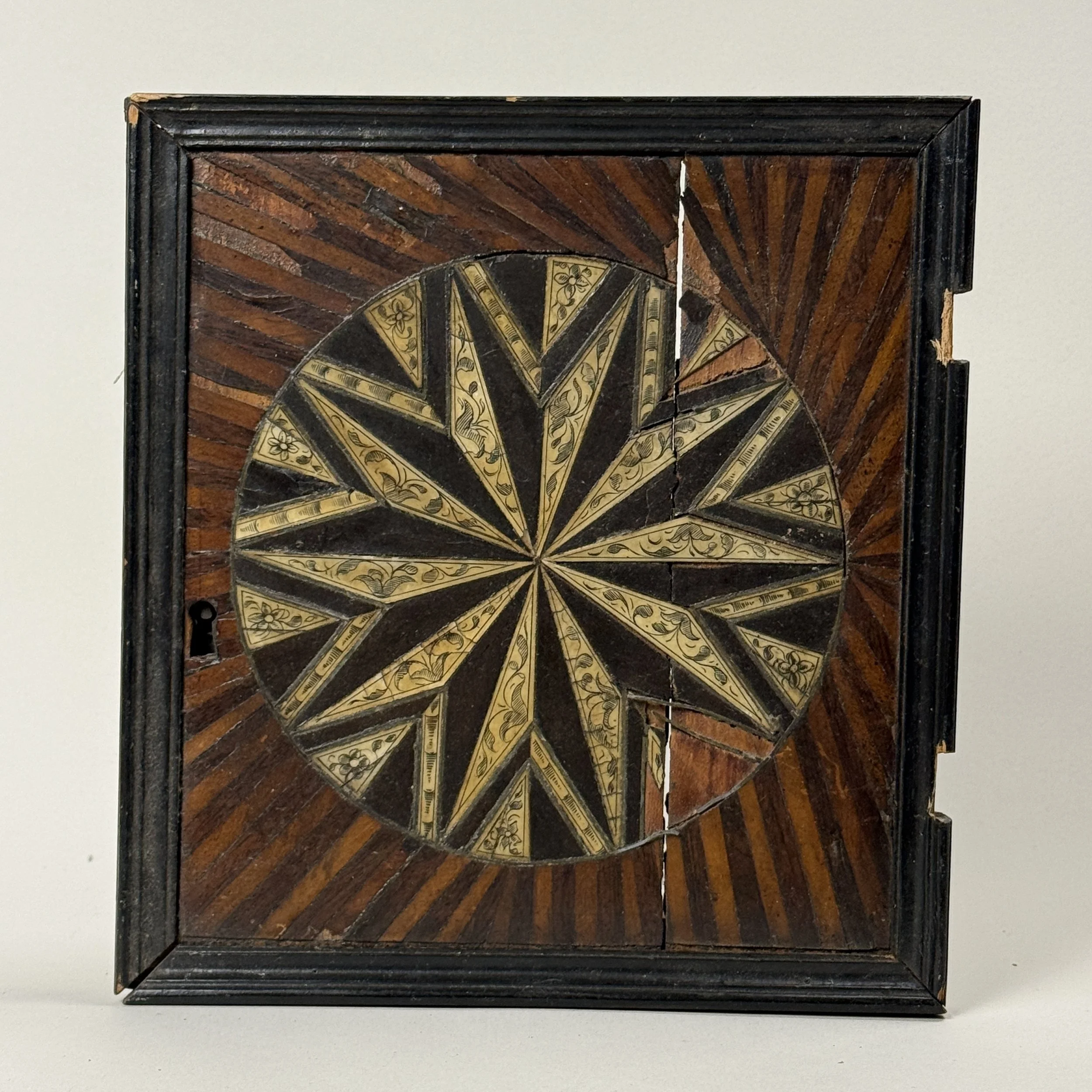 Front view of cabinet doors. Two-tone sunburst parquetry. Hand carved wood.