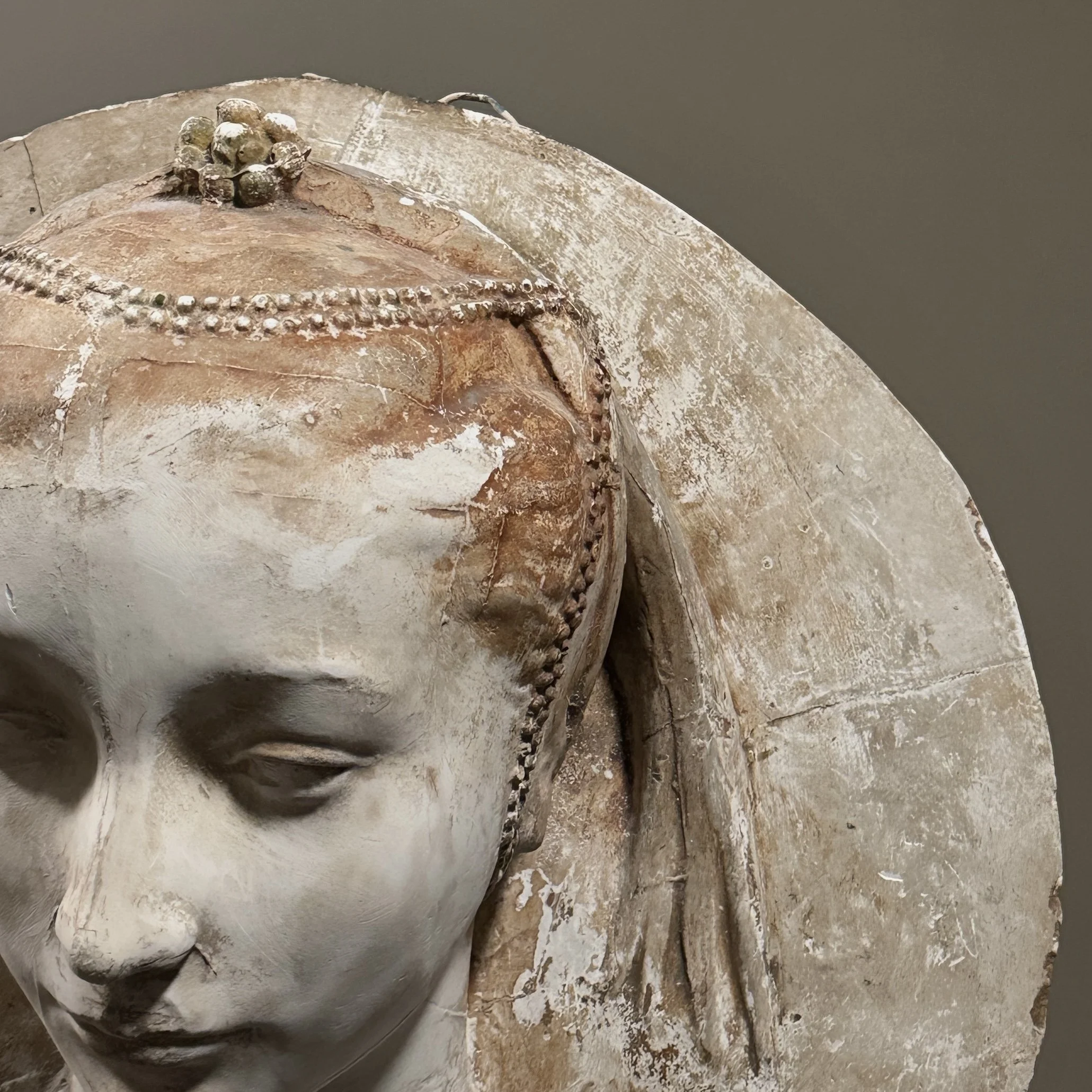 Detail of the female face, hair, and draped headdress.