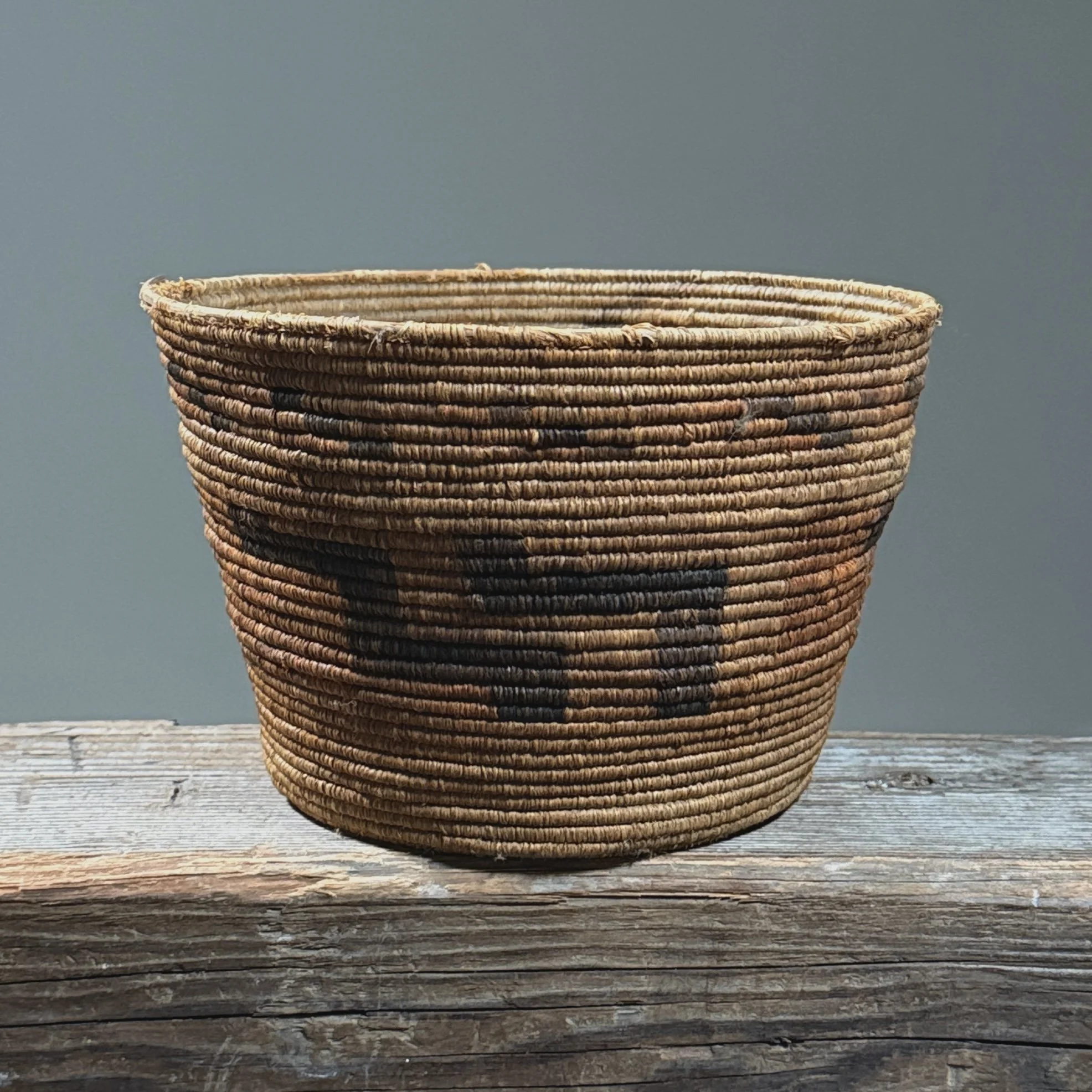 Full frontal view of an antique Tohono O'odham coiled basket with geometric step pattern