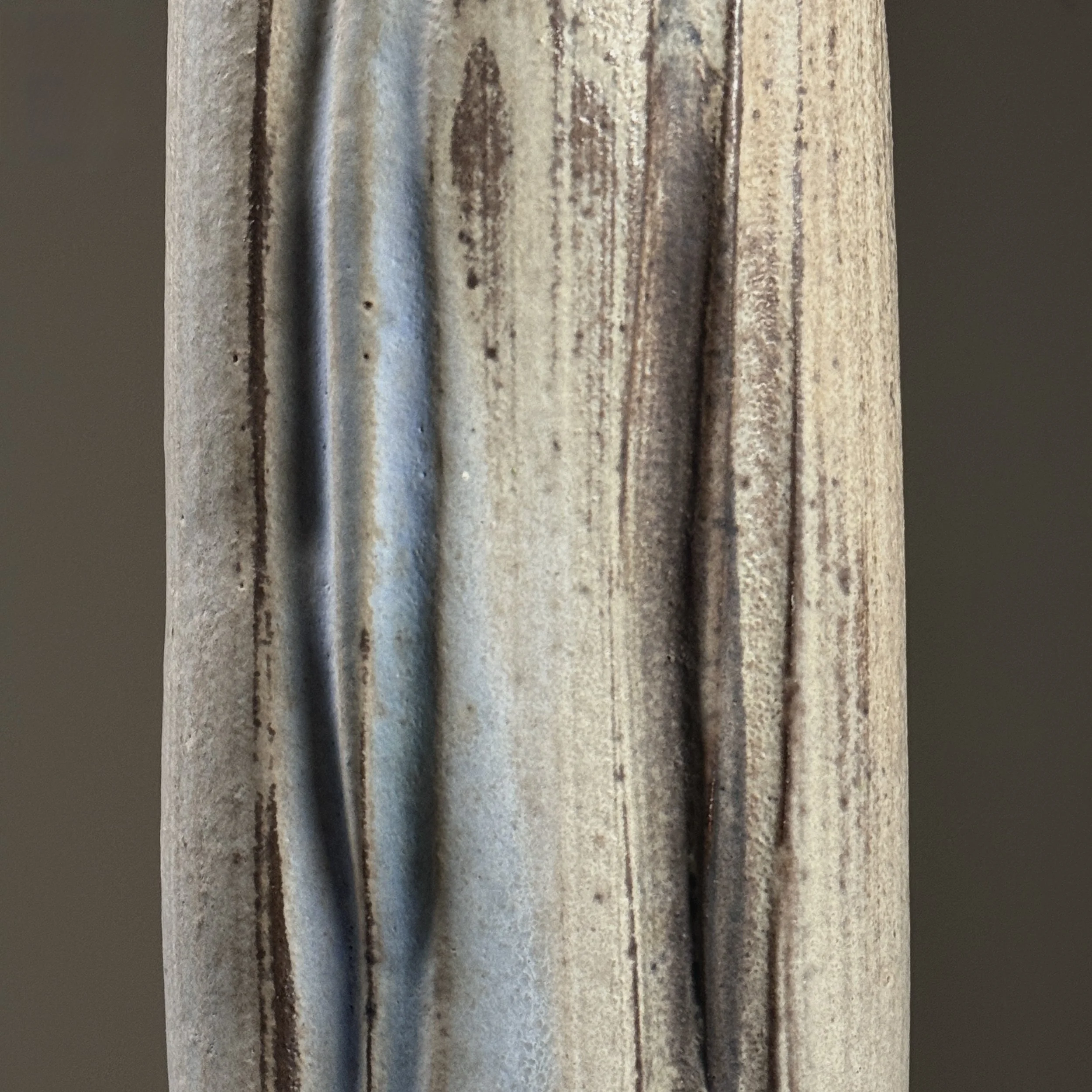 Close-up detail of wood-fired surface effects including pale blue streaks and speckled grey markings