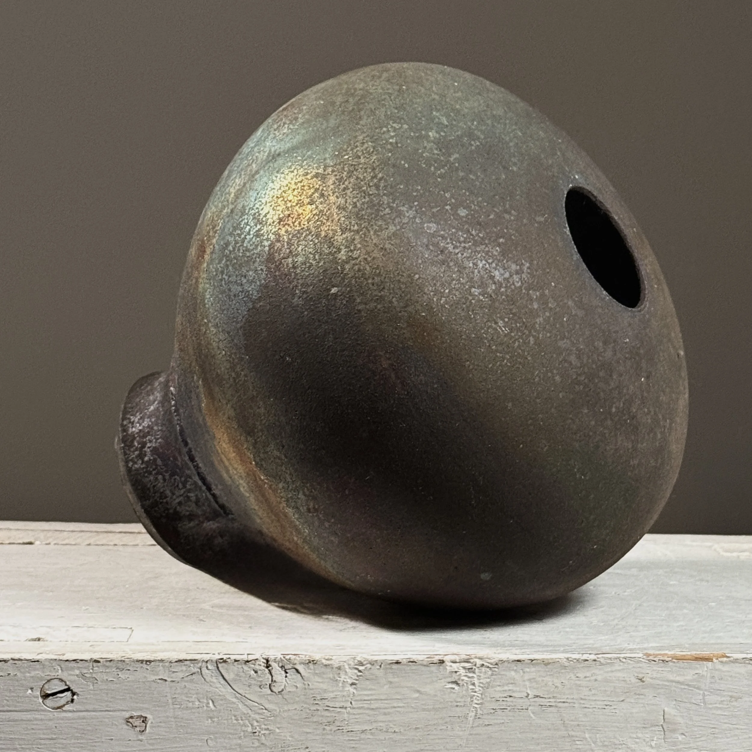 Vintage postmodern raku fired footed black stoneware vessel. 7.18 inches high by 6.75 inches diameter.