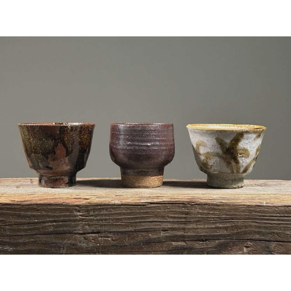 Set of three Japanese modernist yunomi cups. Brown drip glaze left, maroon metallic center, pale purple-pink right.
