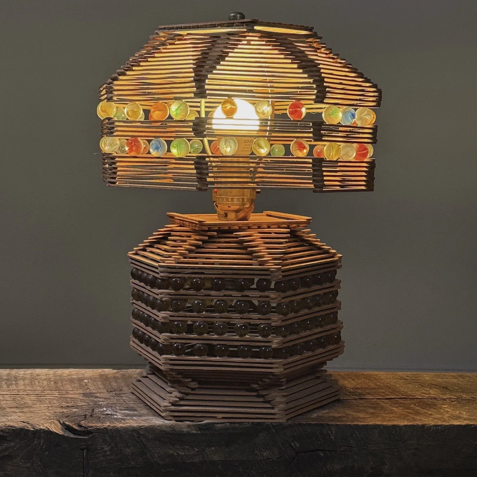 The lamp illuminated, showing light emitted through its lattice shade and structure.