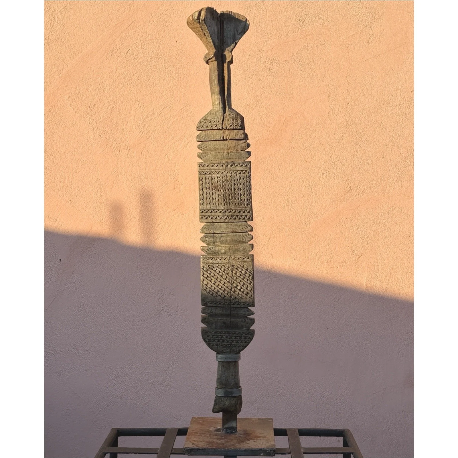 Full view of an antique Tuareg hand-carved wooden tent pole on custom iron stand.
