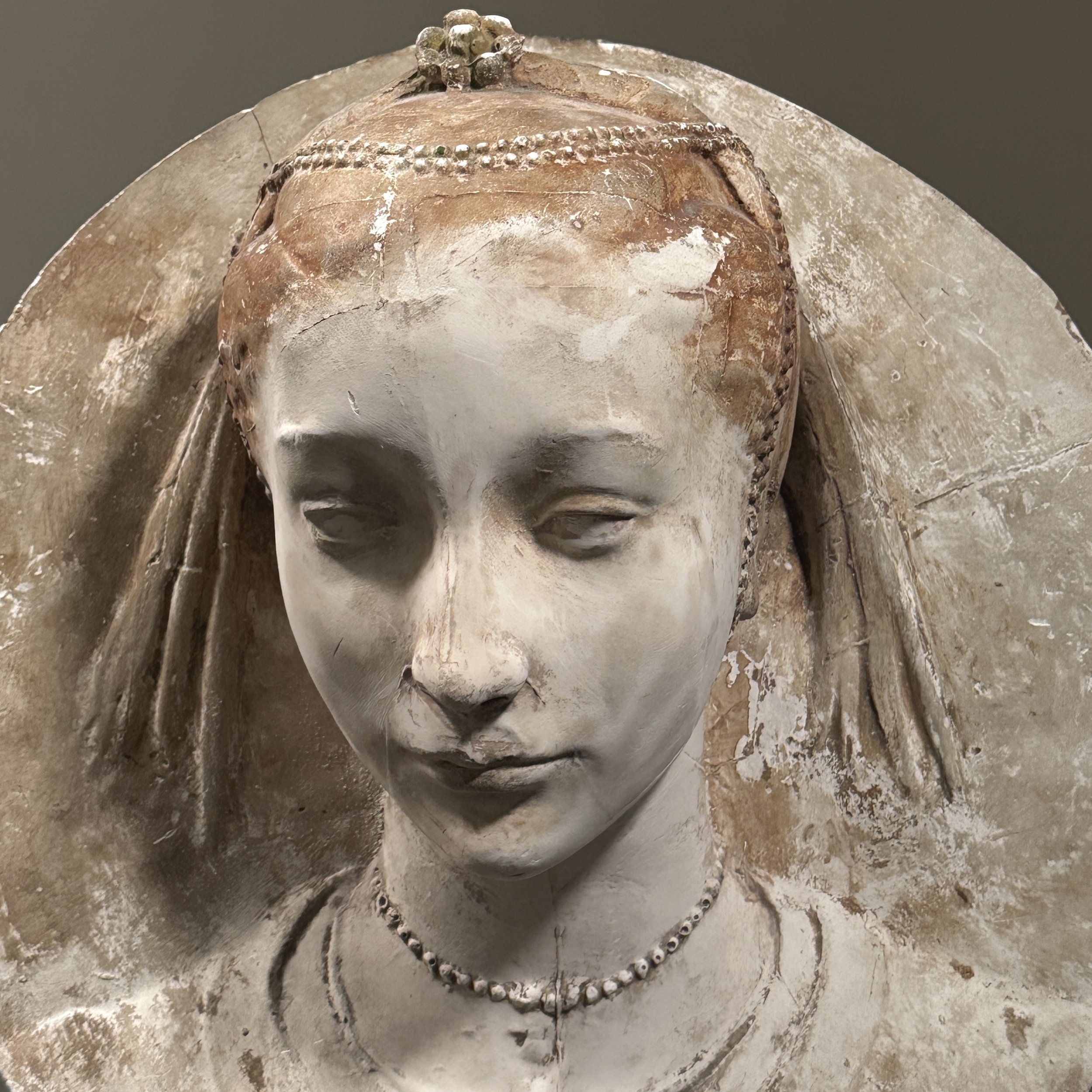 Detail of the female face, hair, and draped headdress.