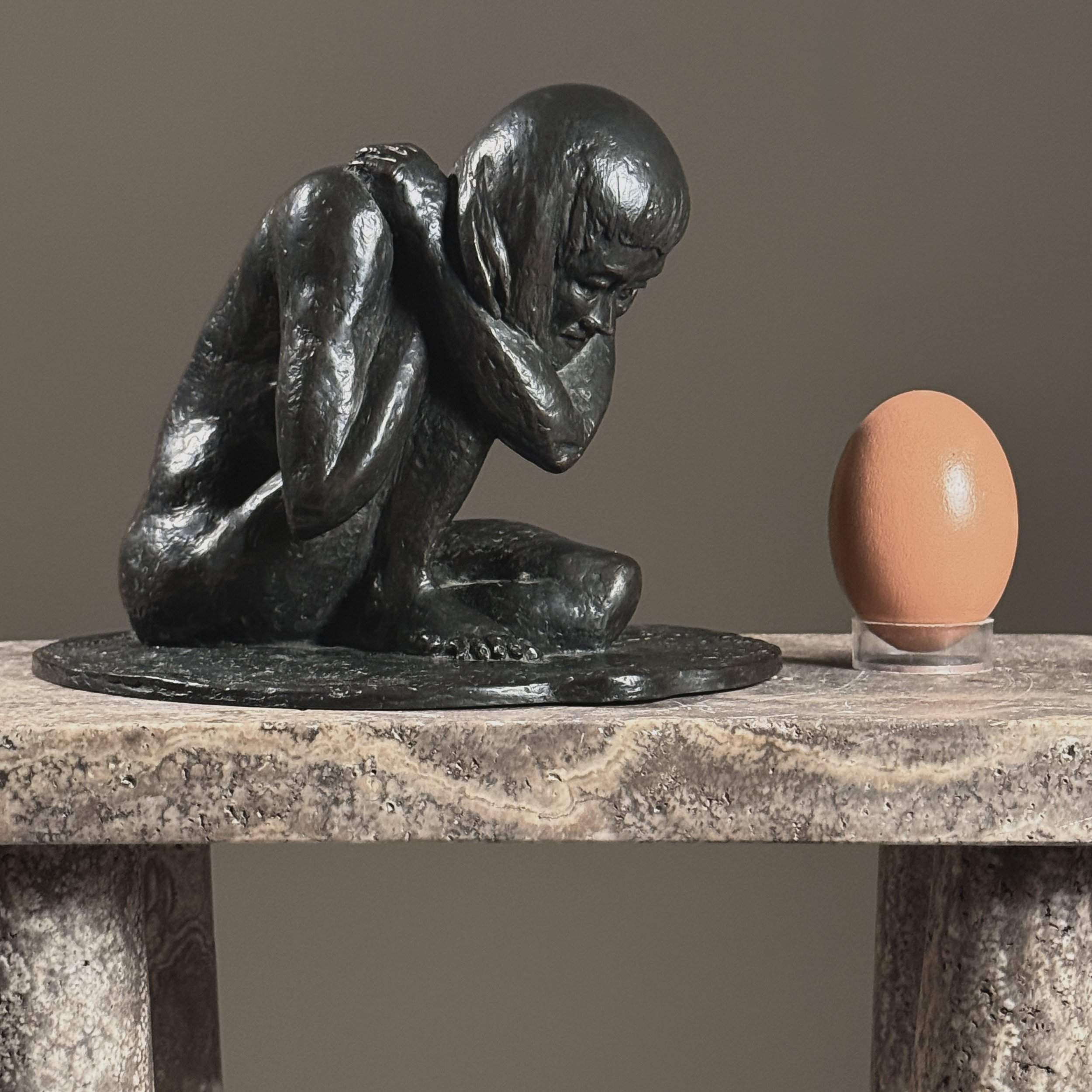Side profile of a vintage bronze crouching nude sculpture by American artist Alma Helbig Hobson With egg for size reference.