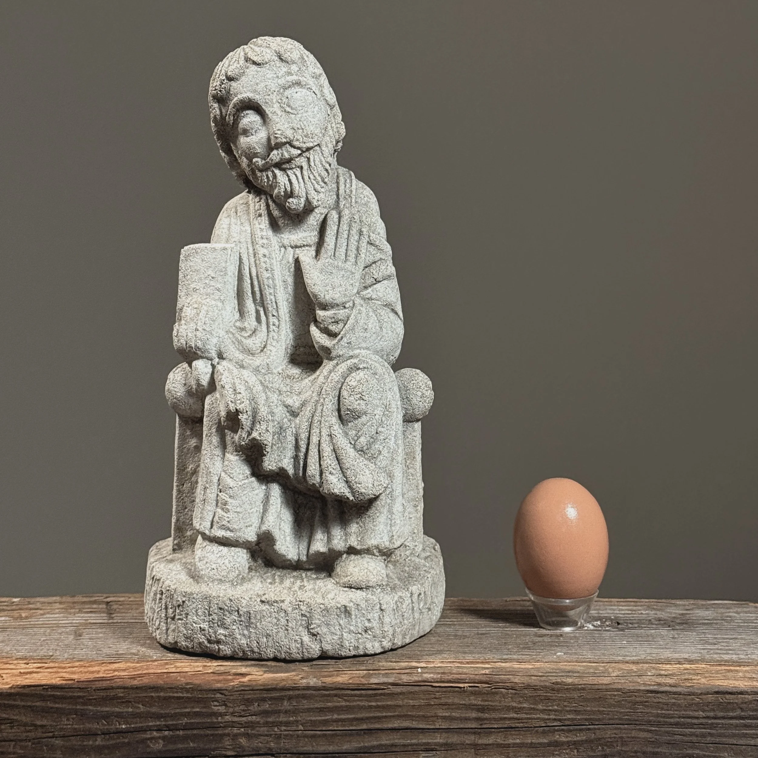 Front view of a Byzantine-style limestone sculpture of Saint Francis of Assisi With egg for size reference.