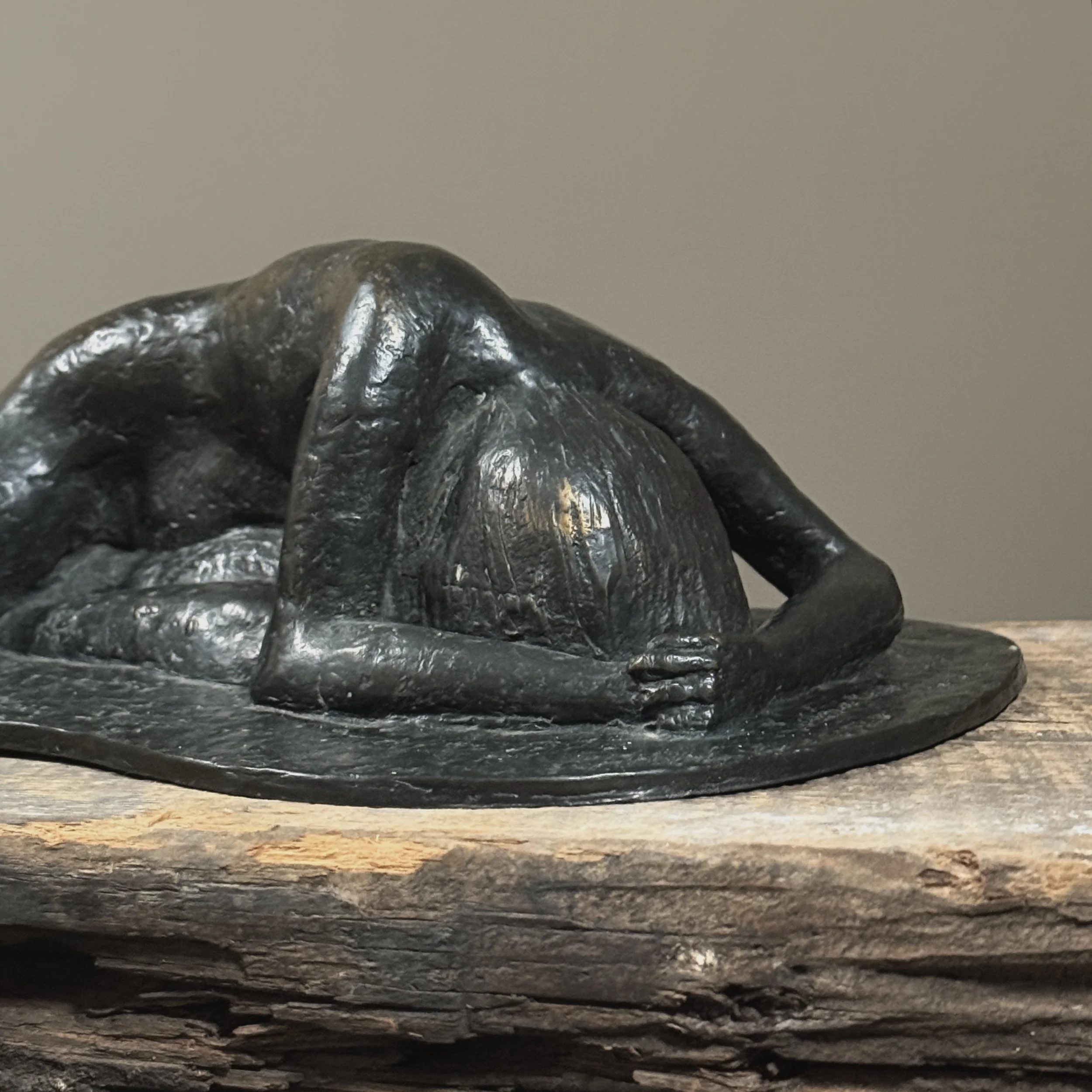 Close-up detail of the figure with head buried in arms.