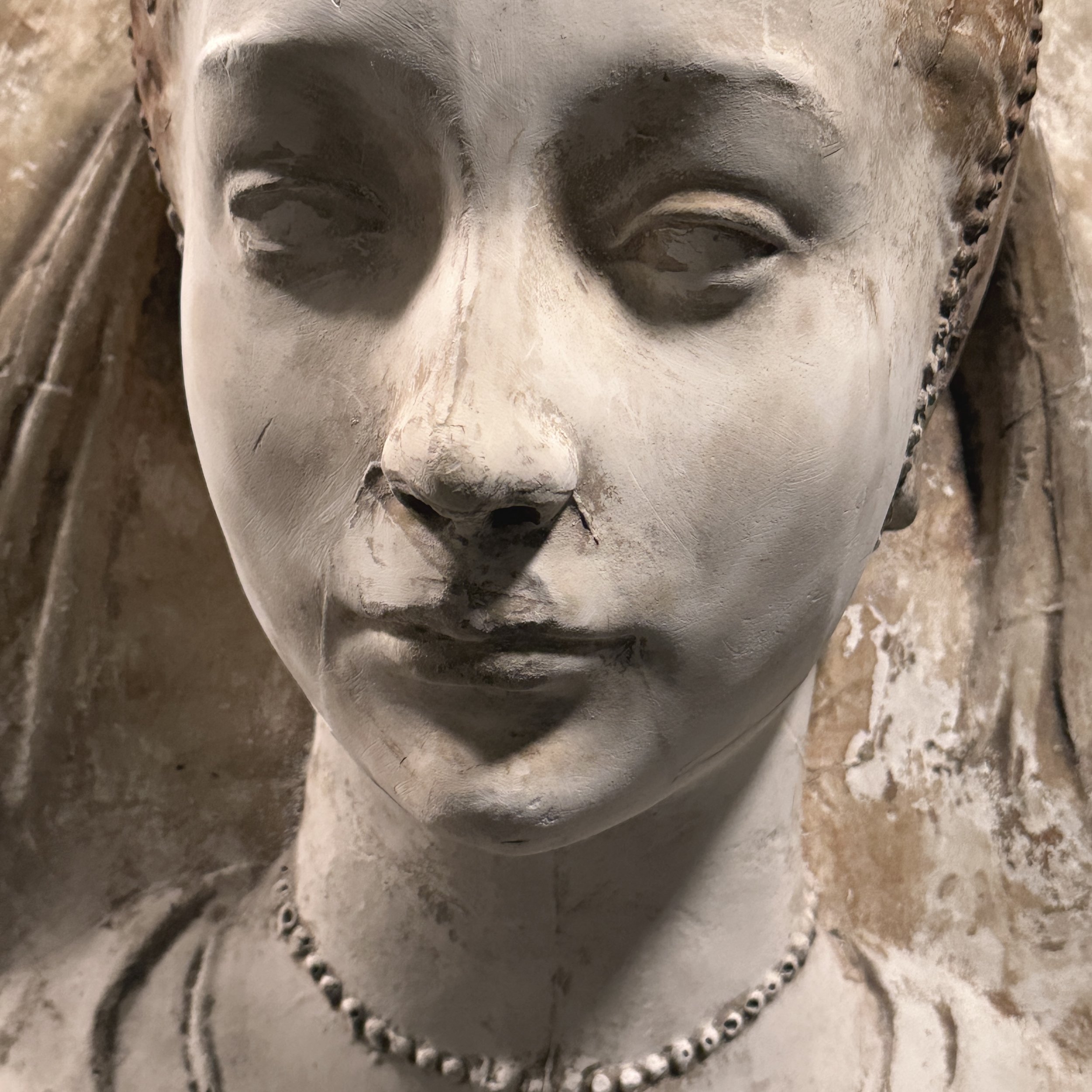Detail of the female face, hair, and draped headdress.