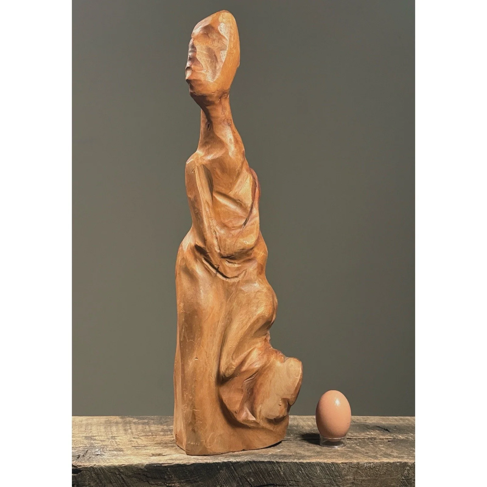 Full frontal view of a vintage abstract folk art figurative root sculpture with natural wood patina with egg for size reference.