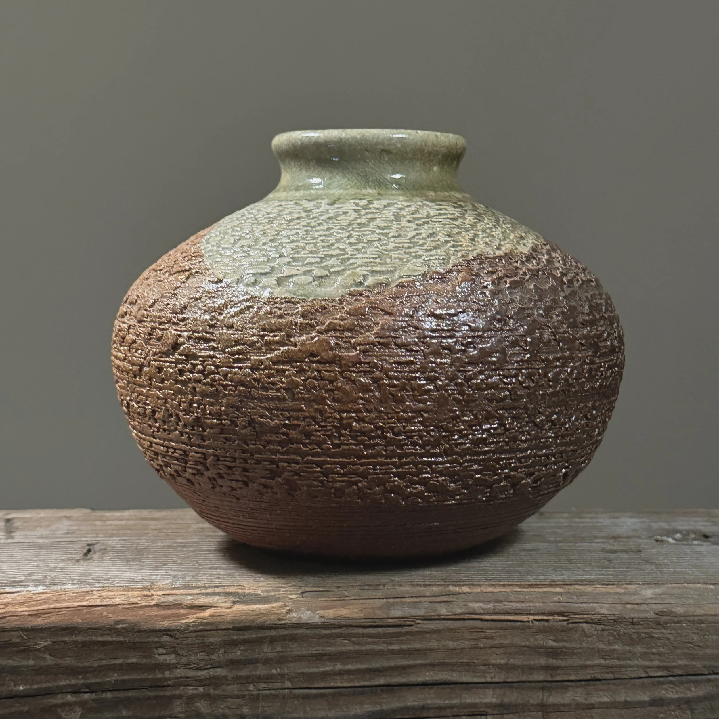 Front view of a Japanese modernist stoneware vase with textured brown and celadon glaze.