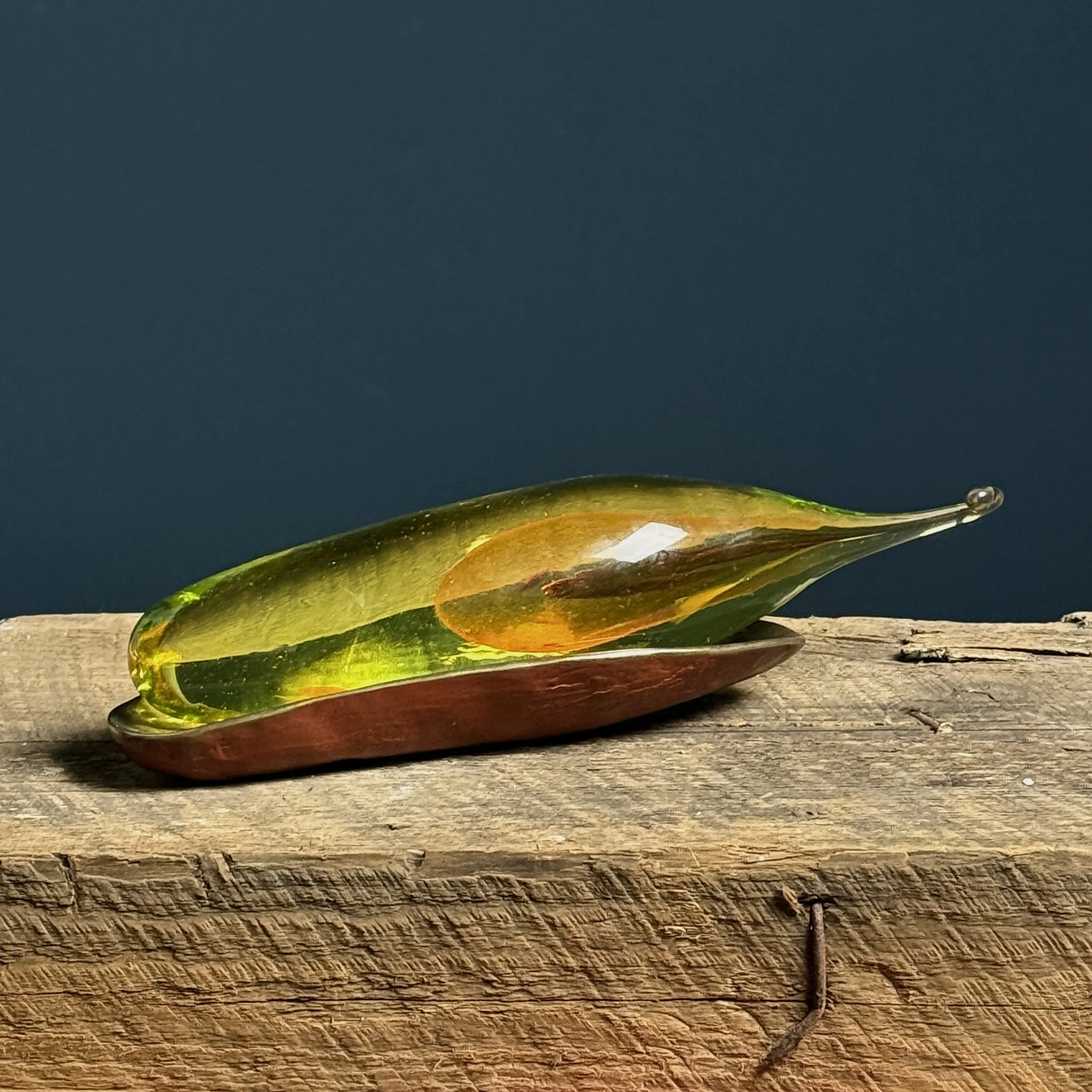 Signed bronzed cradle holding amber, clear and yellow hand-blown glass seed sculpture by Catherine Vamvakas Lay