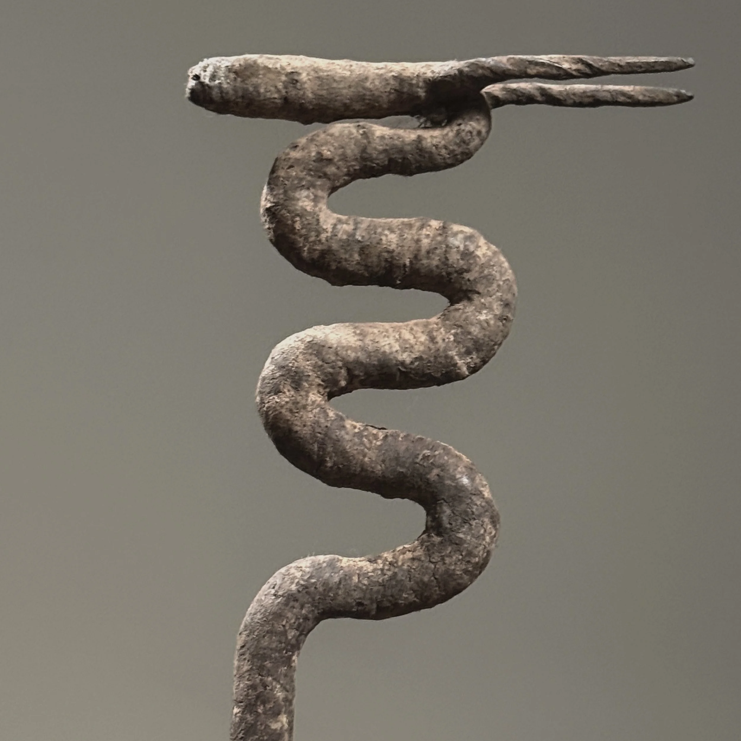 Close-up of antelope head. Wrought iron silhouette rising above snake body.