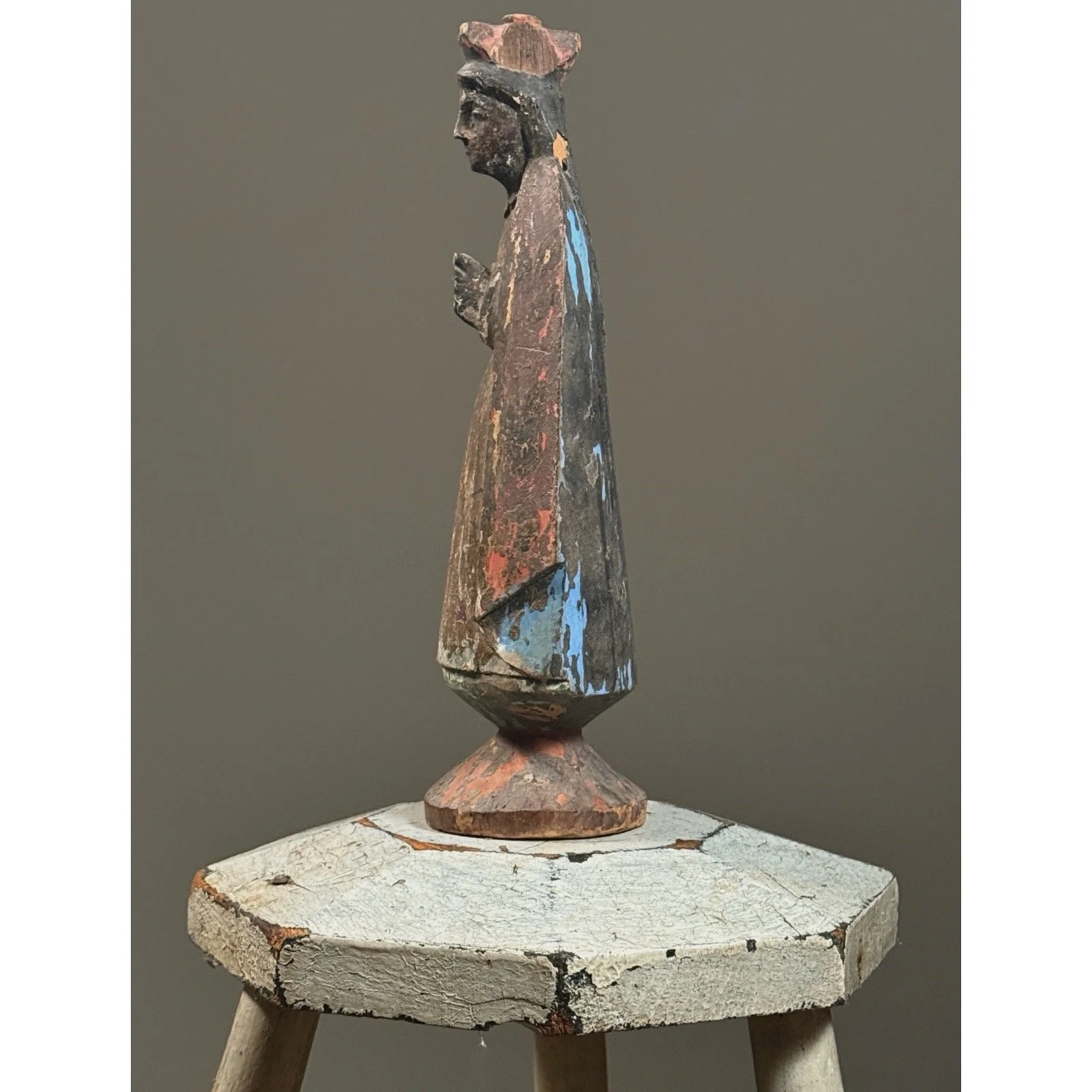 Profile view of the santo, showing the carving of the figure's profile, hood, and tapered base.