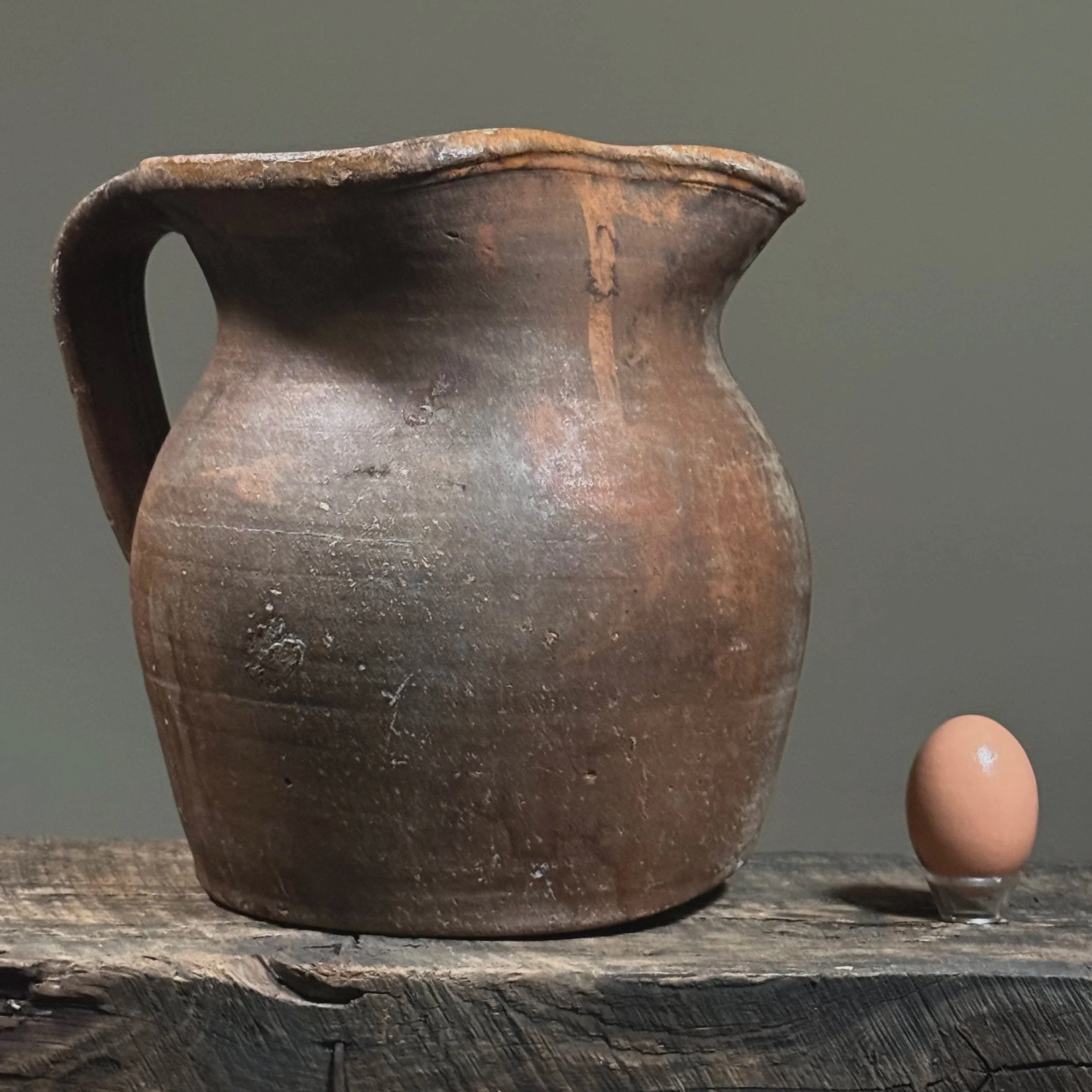 Side profile of Vidigueira redware pitcher with warm earthy tones With egg